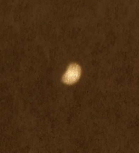 A bright spot on the paper of a pigeon-hole camera showing the sun as it is partially covered by the moon.