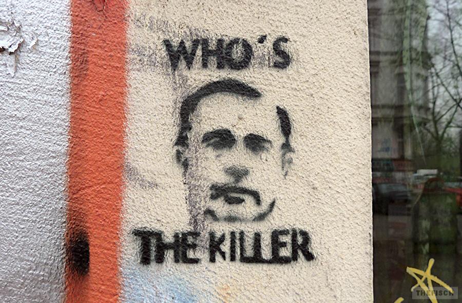 Ein Stencil auf hellem Hintergrund mit einem männlichen Porträt in der Mitte. Oberhalb des Kopfes steht „WHO'S“, unterhalb steht „THE KILLER".