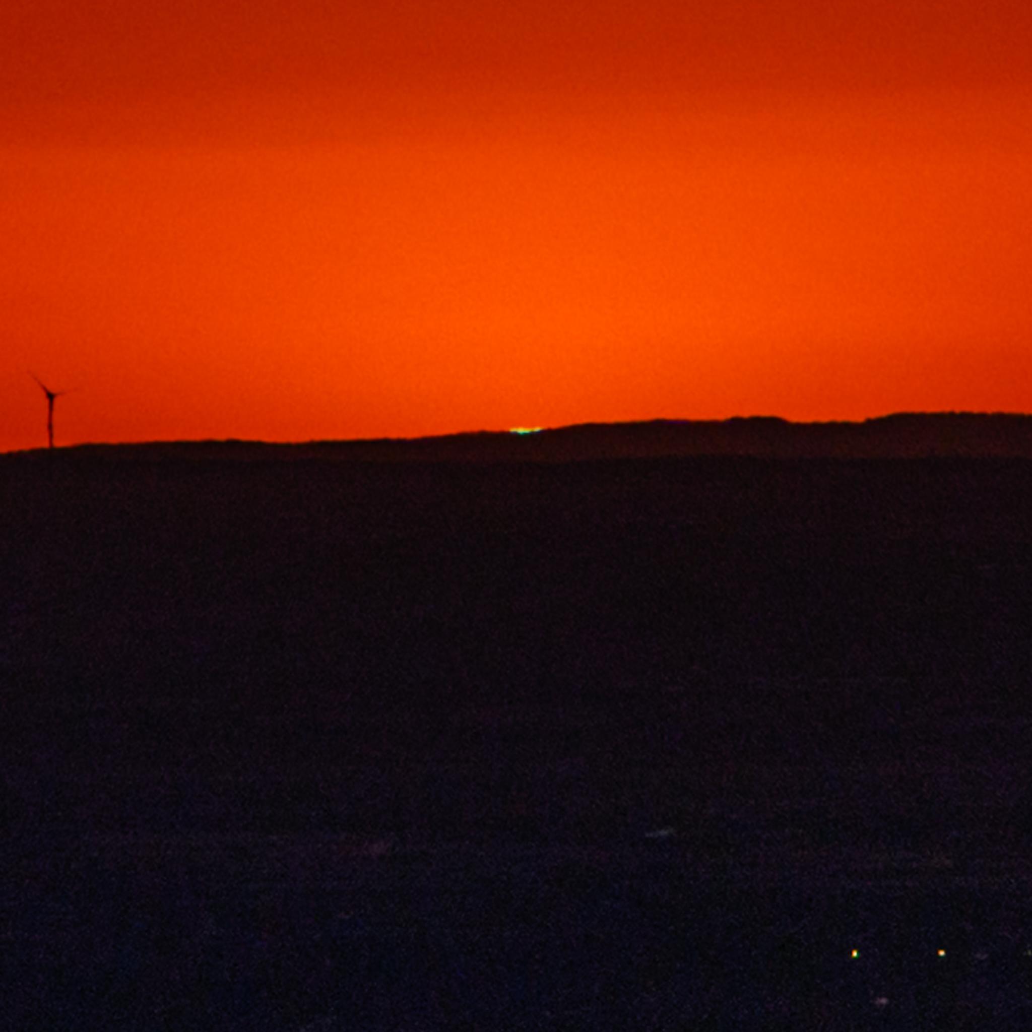 A crop of the same picture, now enlarging the little bit of green light from the Sun right on the horizon.