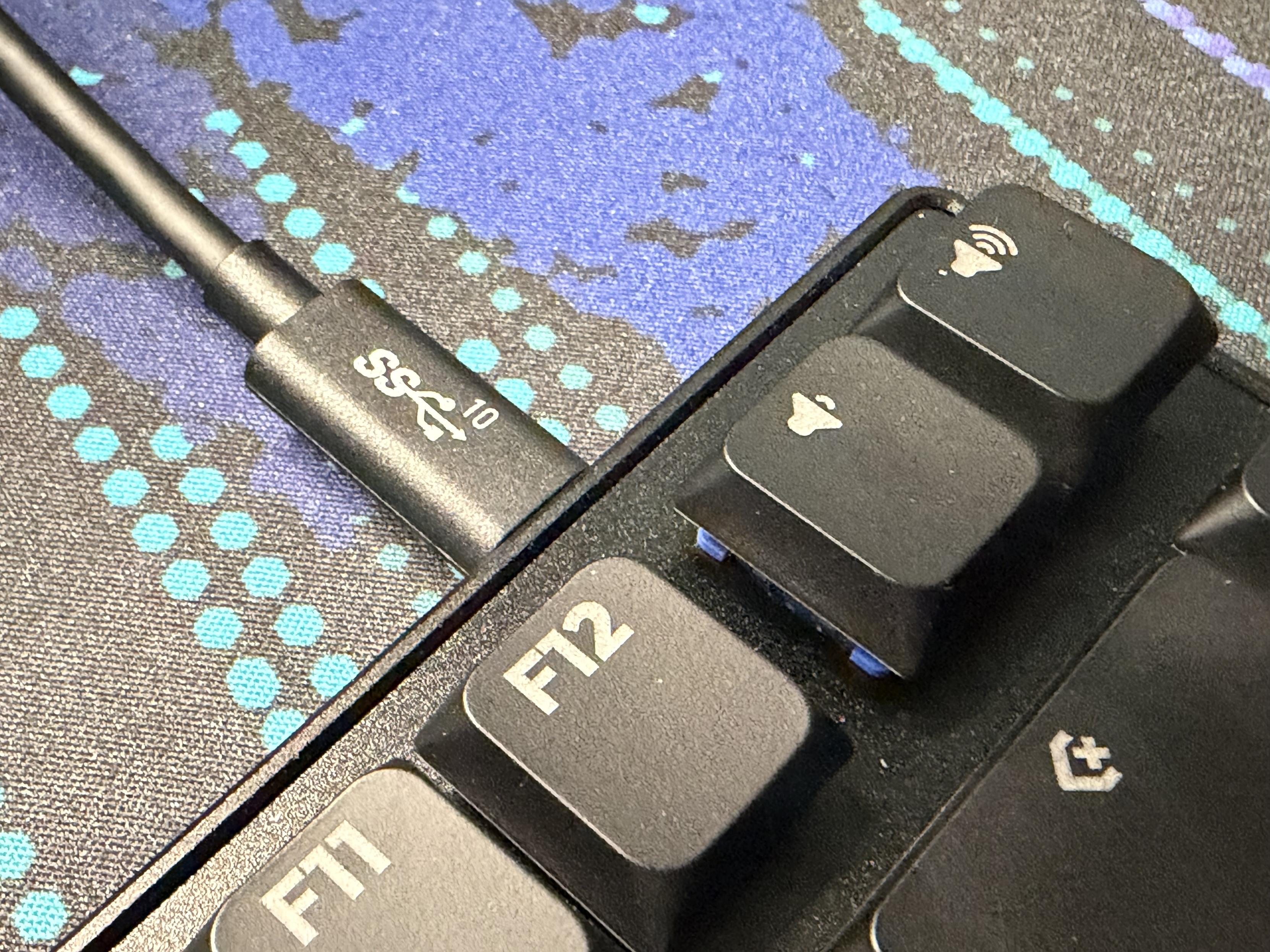 a close-up of a the corner of a keyboard with a 10Gbps cable plugged in to it