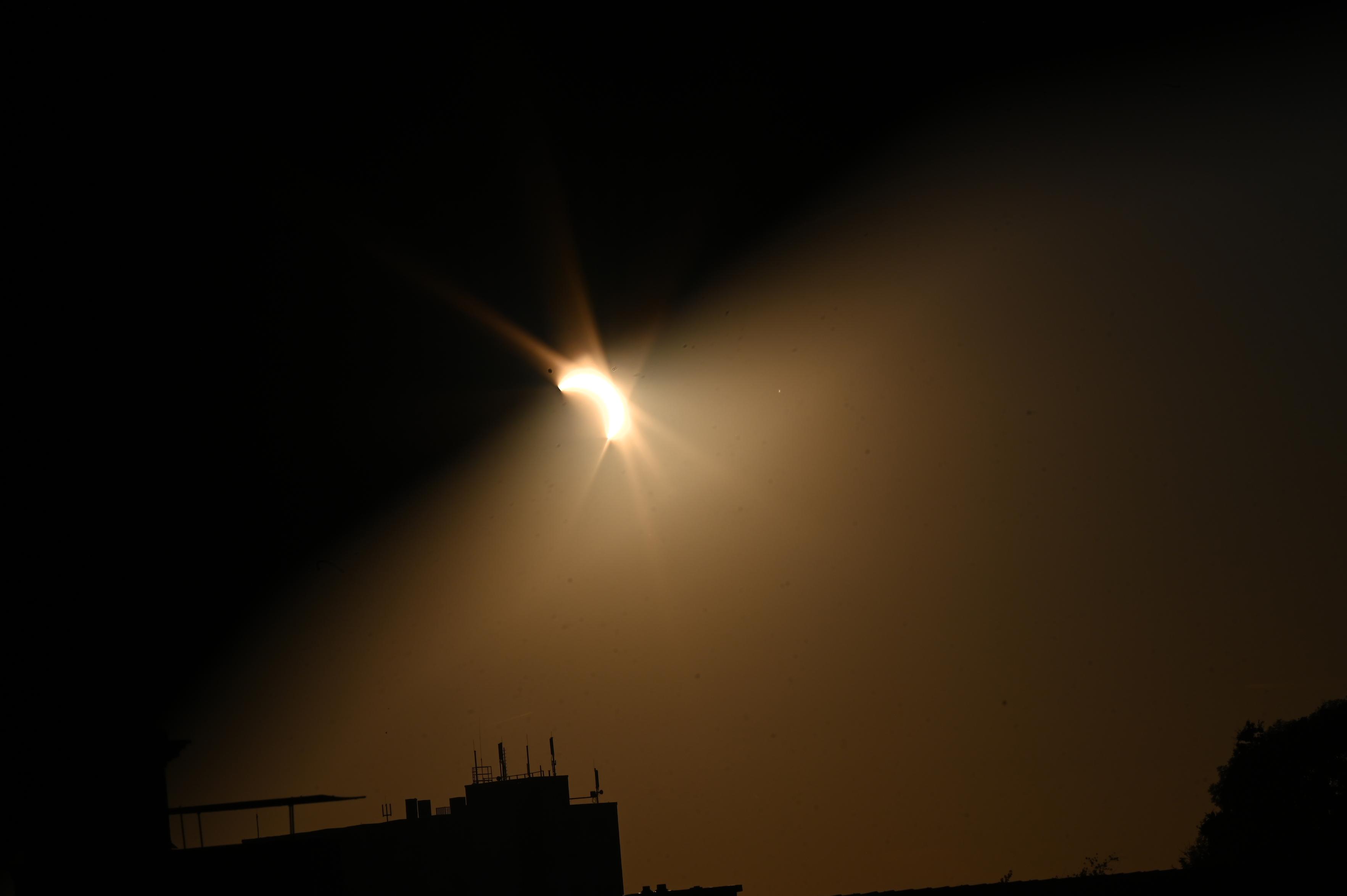 Sonnenfinsternis oben ist das Bild dunkler unten sind teile von Siluetten von einem Haus mit Antennen und rechts unten einer Baumkrone zu sehen.

Bei dem Bild wurde mit der Hand (dunkelheit oben) die Sonnenblende verstärkt)