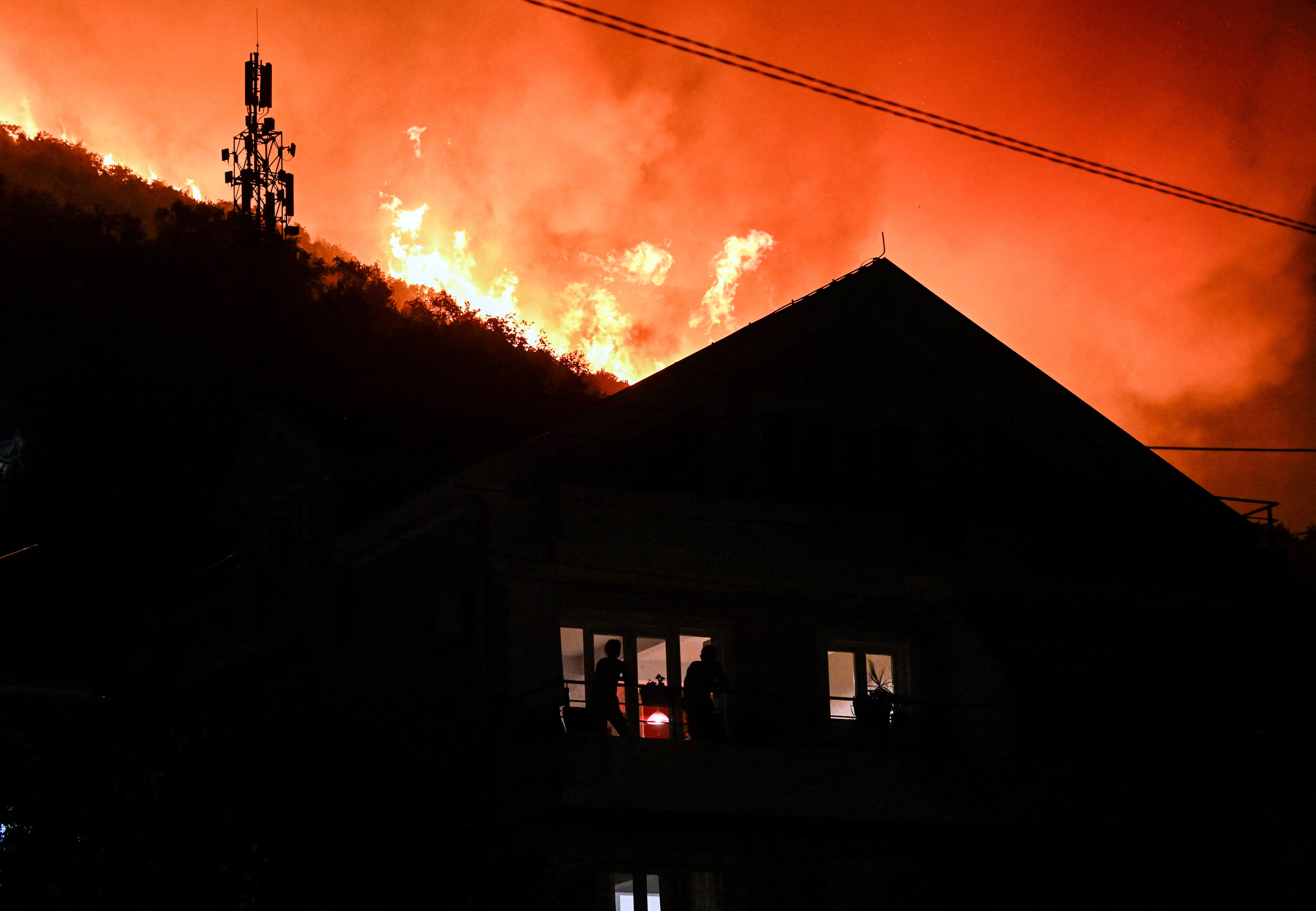A firefront approaching an inhabited house at night.