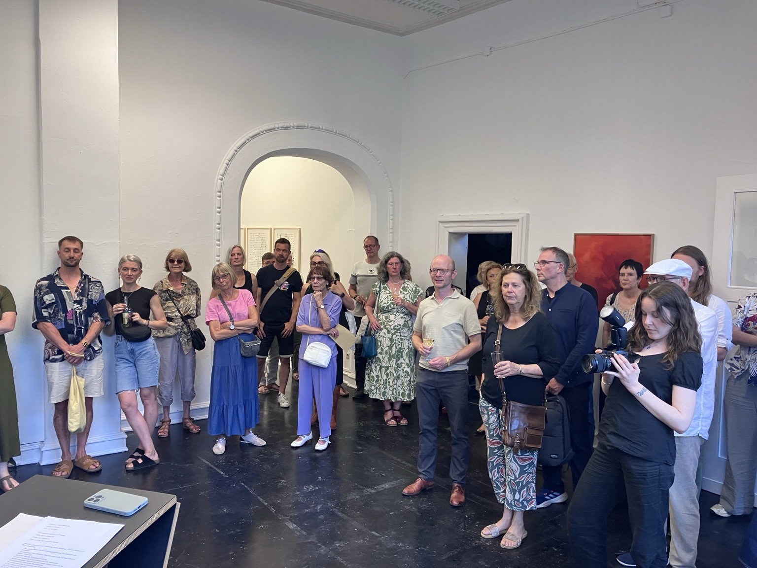 Mit großem Interesse lauschen die Menschen der Ausstellungseröffnung Present Perfect mit den einführenden Worten von Anja Timpner und Carolin Knüpper