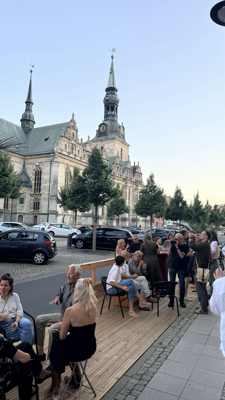 Im Anschluss genießen die Besuchenden die Atmosphäre vor dem Prinzenpalais in Wolfenbüttel mit Blick auf die Hauptkirche auf dem Parklet