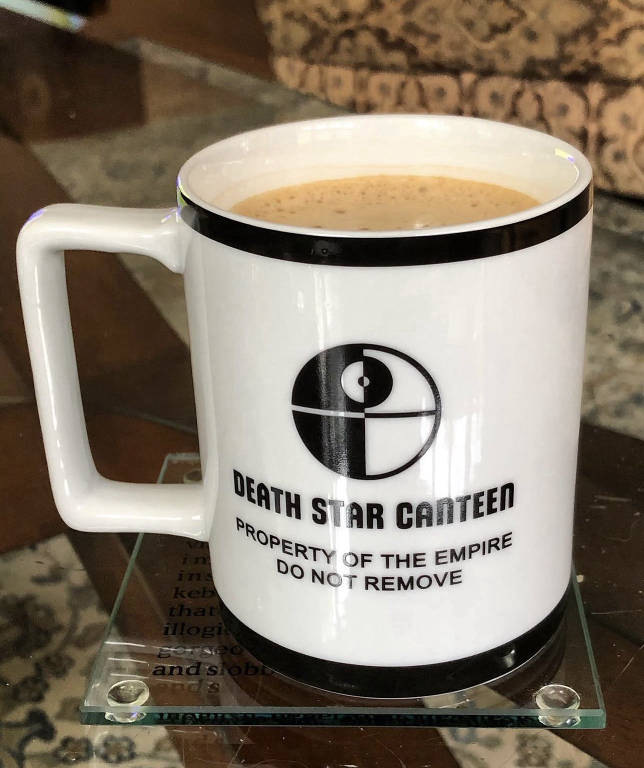 A white coffee mug filled coffee engraved in black with the words DEATH STAR CANTEEN PROPERTY OF THE EMPIRE, written in homage to the Star Wars universe