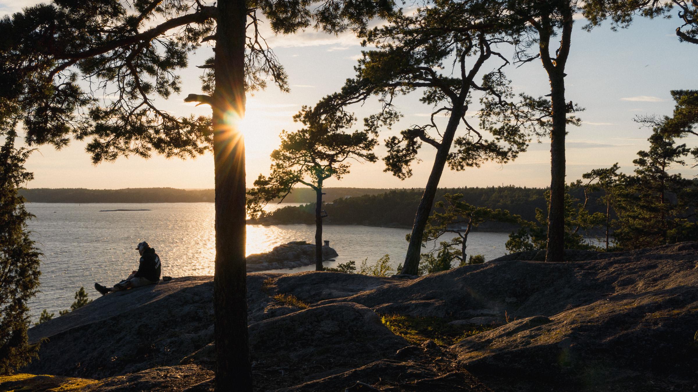 Mann sitzt auf einem Felsen am Schärenmeer