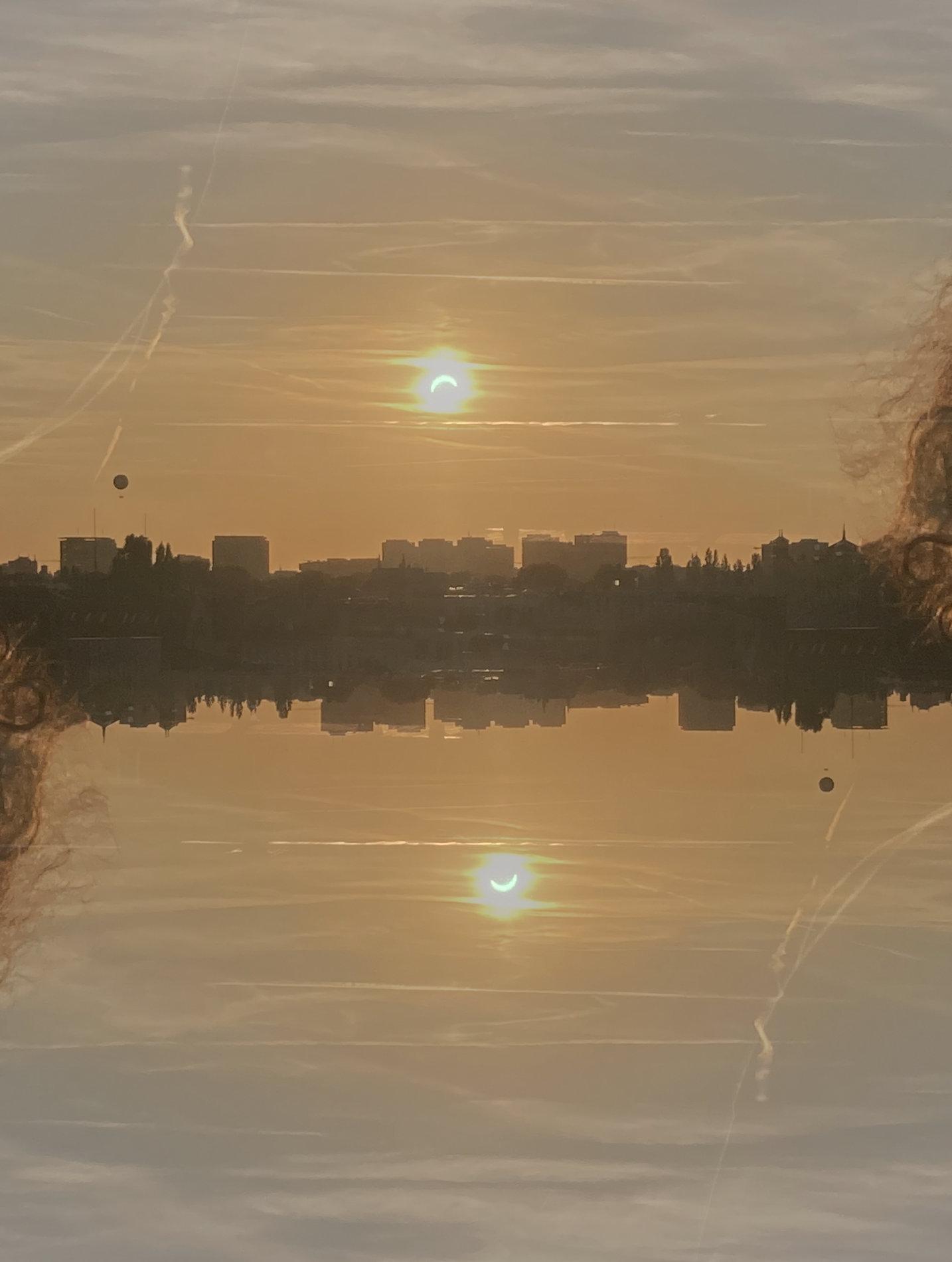 cityscape shot flip-flopped (rotated 180°), overlayed over the same image; you get a center "band" of city, two balloons; two suns, exactly aligning with the crescent moons which show how the sun looked weren't it so overexposed