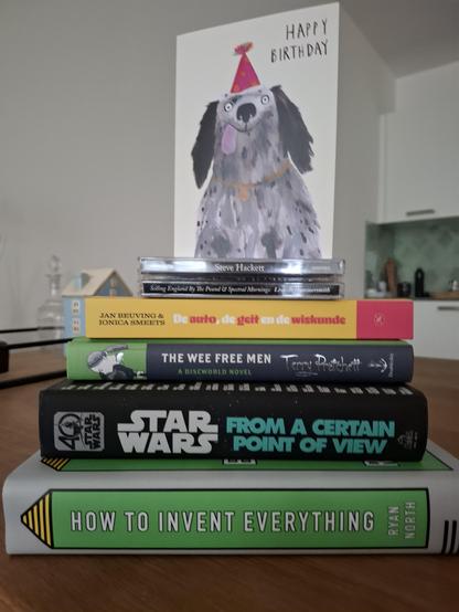 A pile of
* a birthday card with a cartoon dog
* CD Spectral Mornings by Steve Hackett
* Book De auto, de geit en de wiskunde 
* Book The wee free men
* Book Star Wars from a certain point of view
* Book How to invent everything