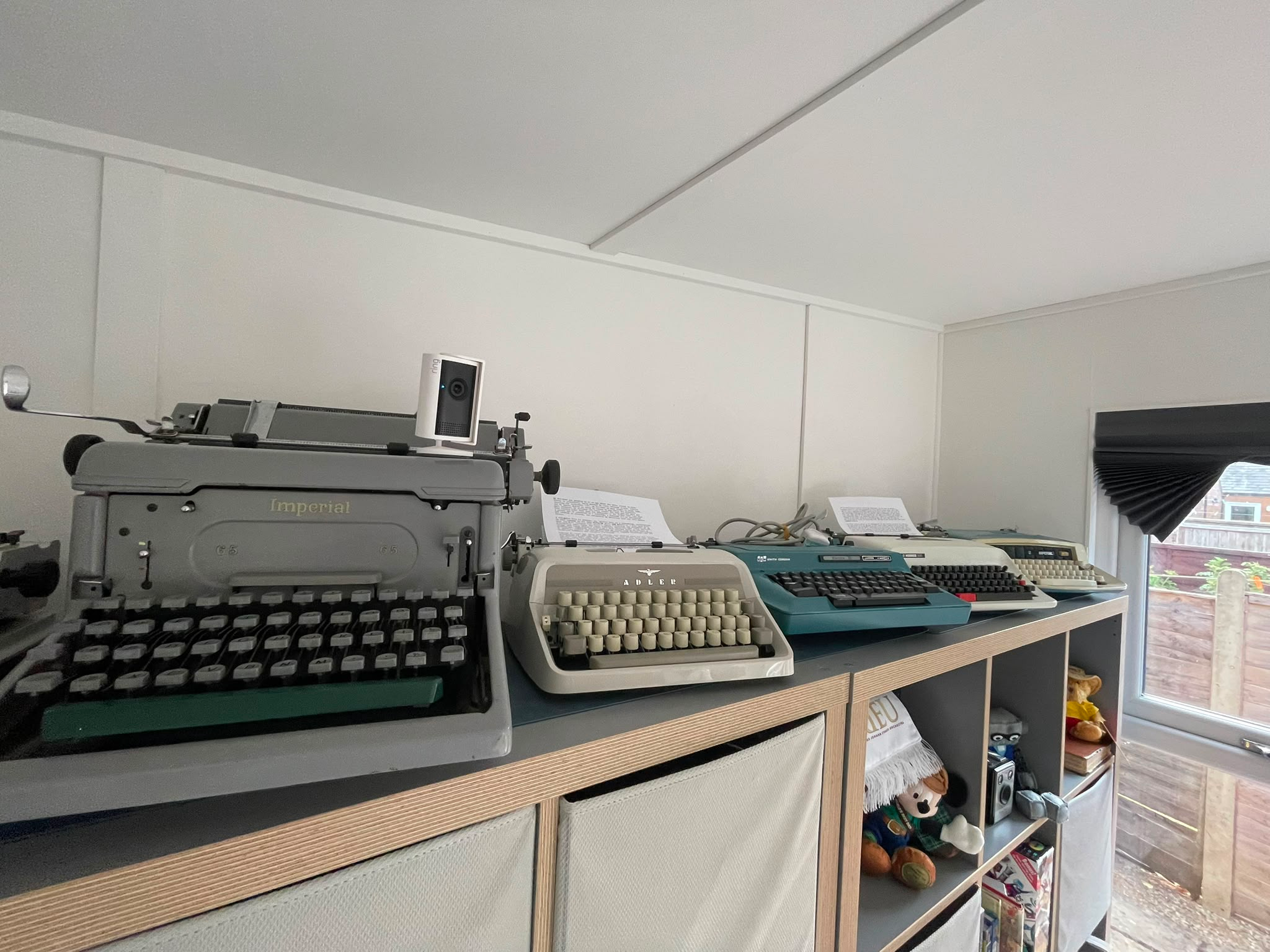 Wide shot of multiple vintage typewriters on top of a storage unit.
