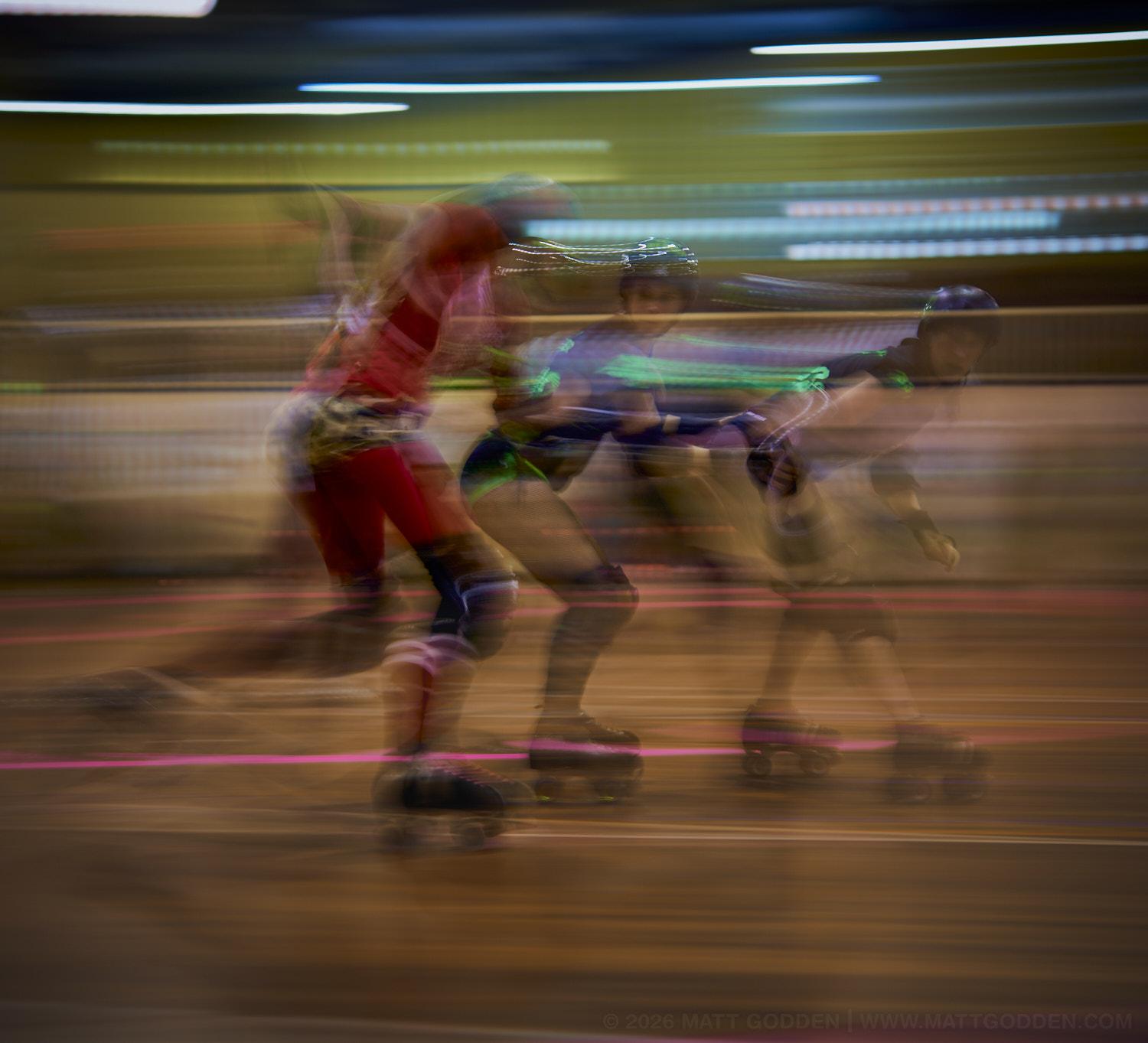 A long exposure image of roller derby competitors from the D'Viants (lime green) and the Screaming Assault Sirens (red). 2013/11/09