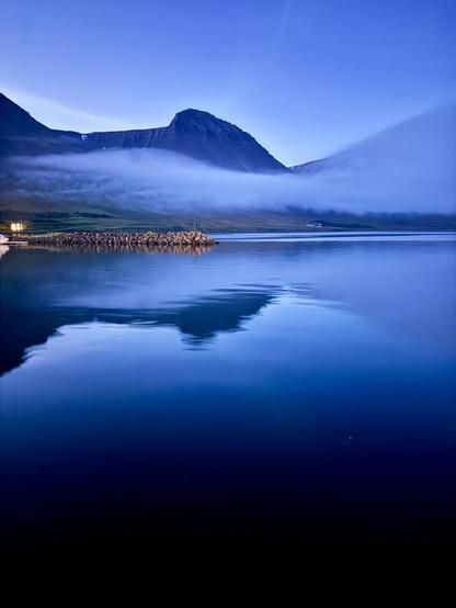 The harbor area of Flateyri with the mountains reflected in the water