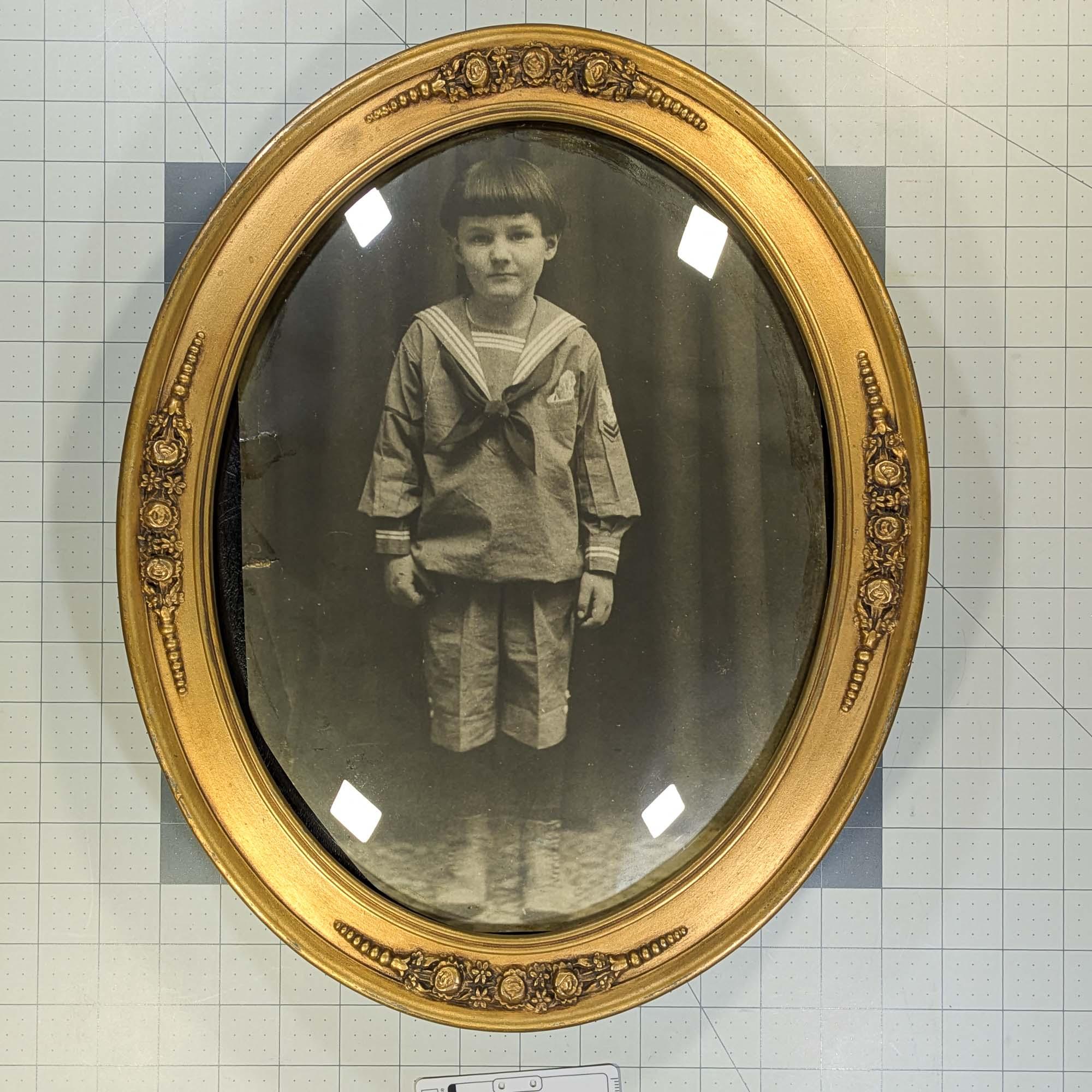 Photo of a young boy wearing a sailor suit in an antique decorative gold bubble glass frame