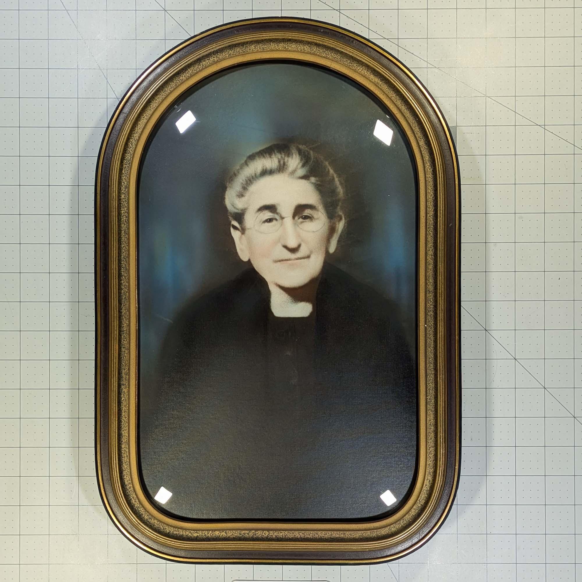 Photo of a older woman with greying hair and spectacles in an antique bubble glass frame