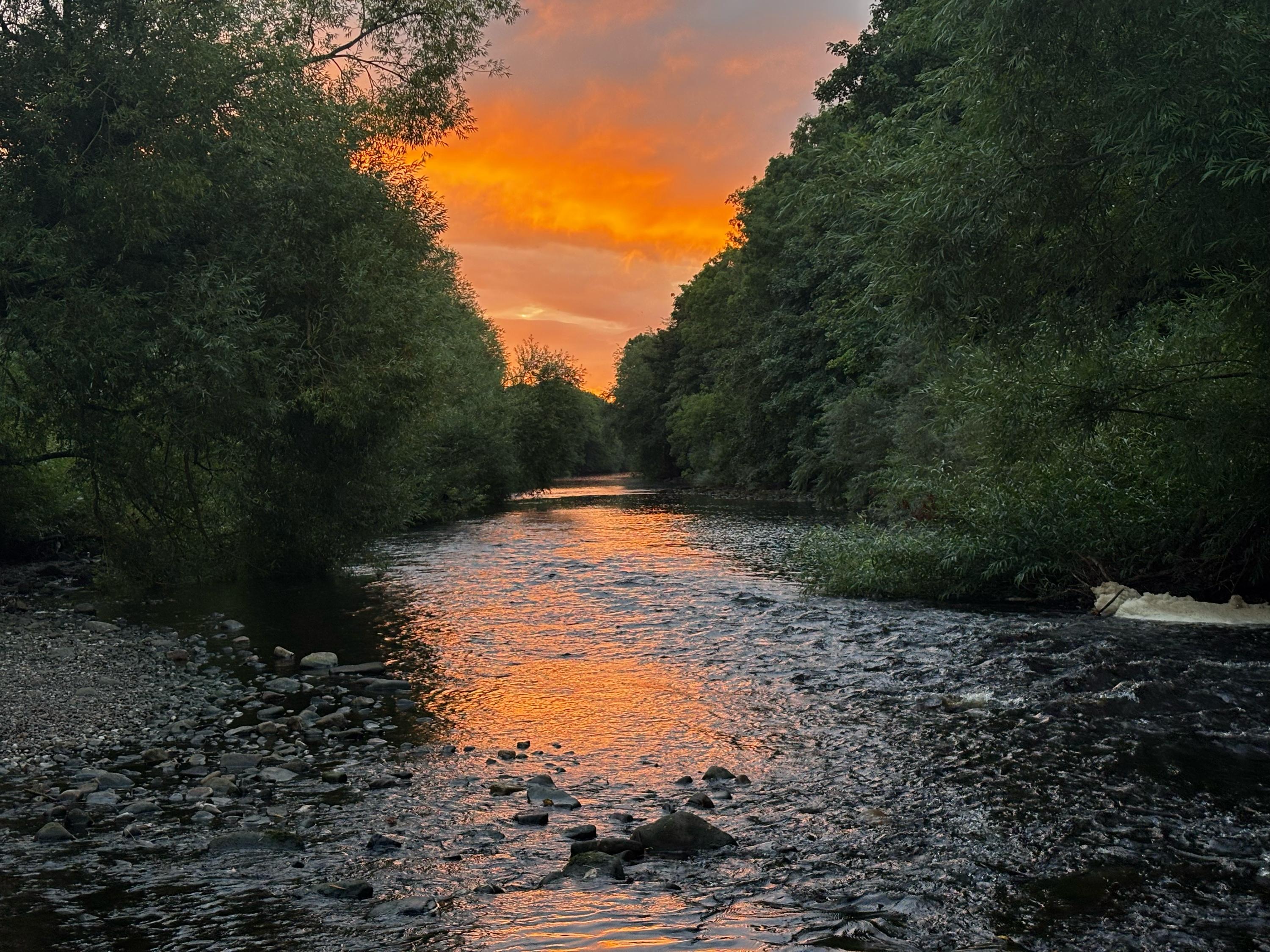 River in the foreground flowing directly east toward the bright orange sunrise.