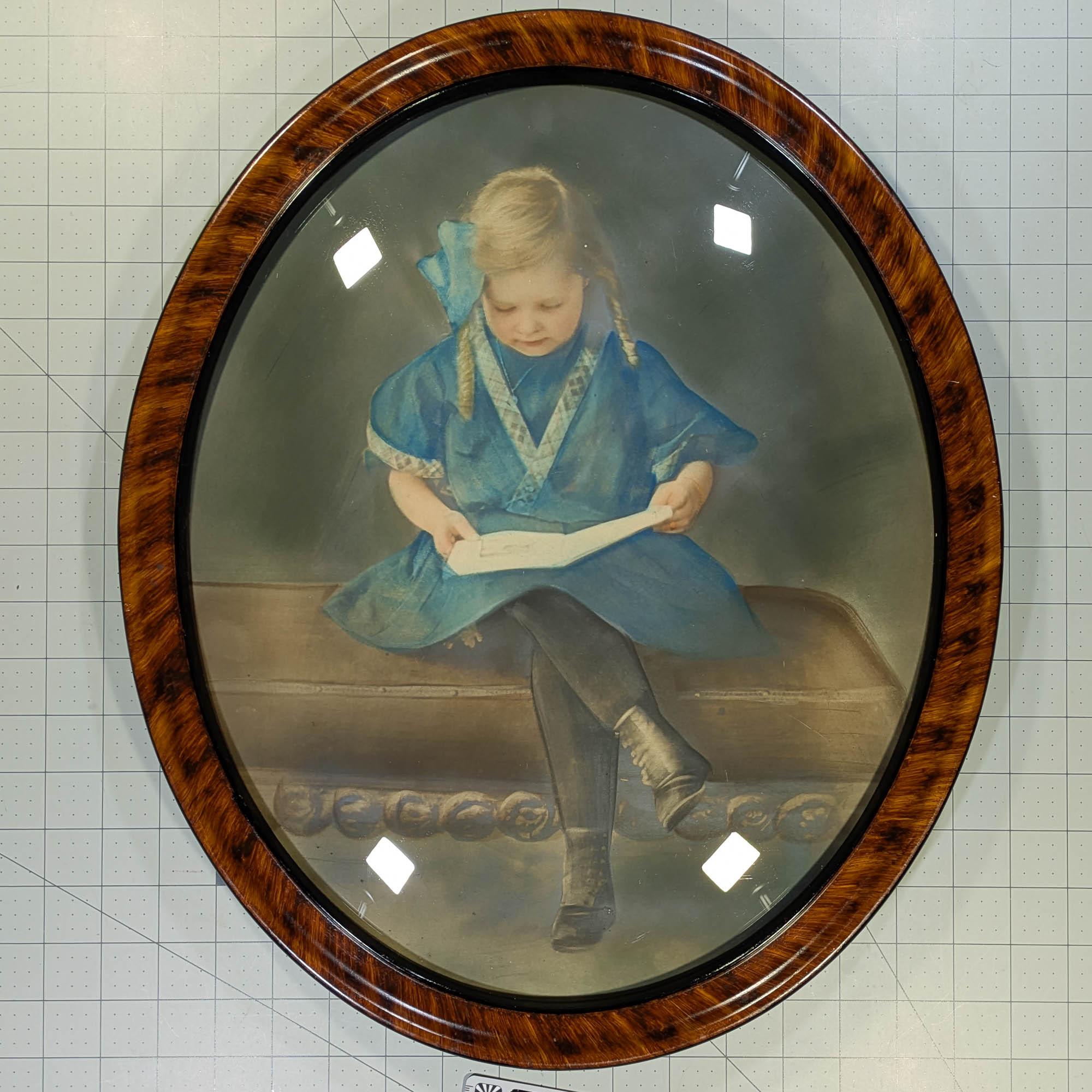 Crayon portrait of young girl with a blue dress and blue bow reading a book in an antique bubble glass frame