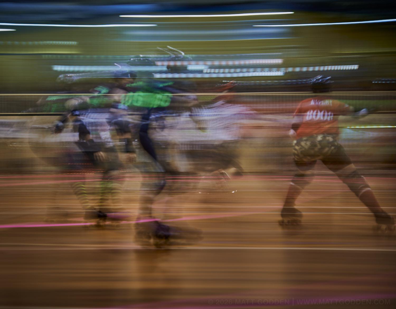 A long exposure image of roller derby competitors from the D'Viants (lime green), and the Screaming Assault Sirens (red). 2013/11/09