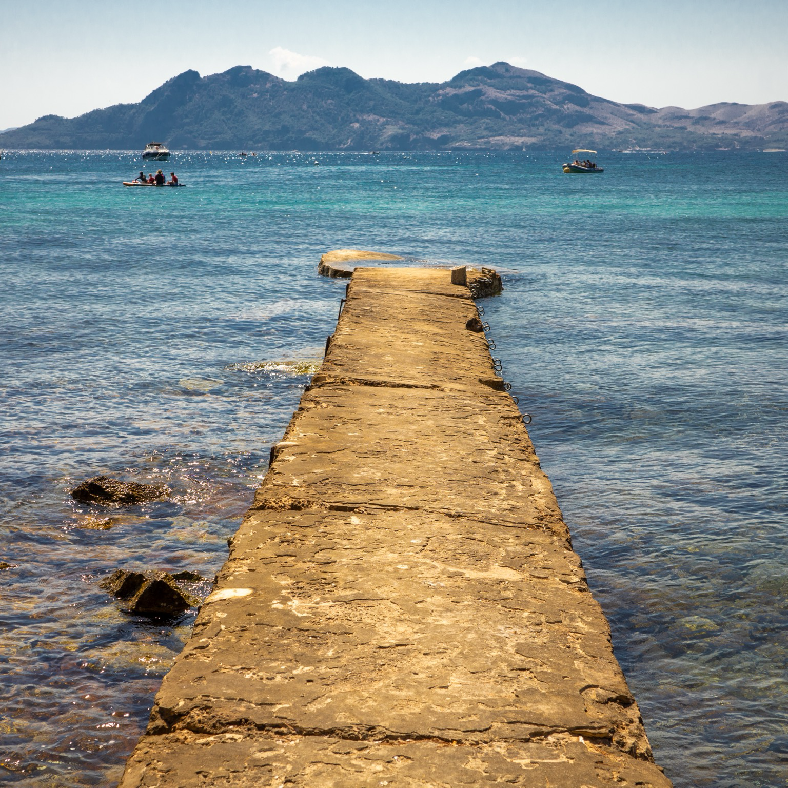 An old pier going off into a blue and turquoise sea