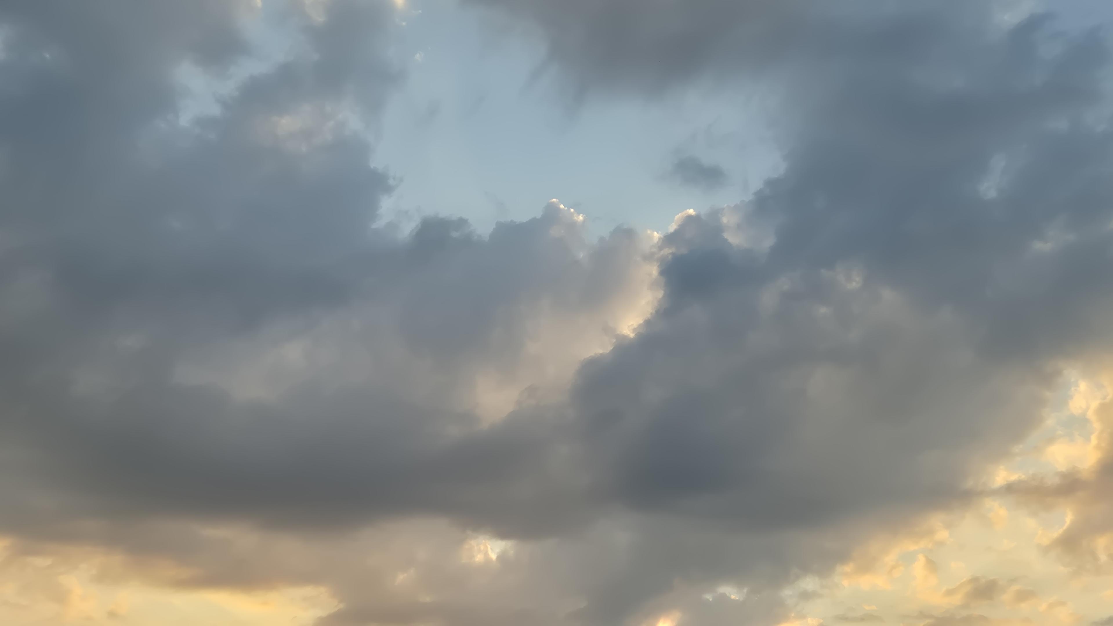 Dunkle Wolken am Abendhimmel mit teilweise weißer Corona. /
Dark clouds in the evening sky, some with a white halo.