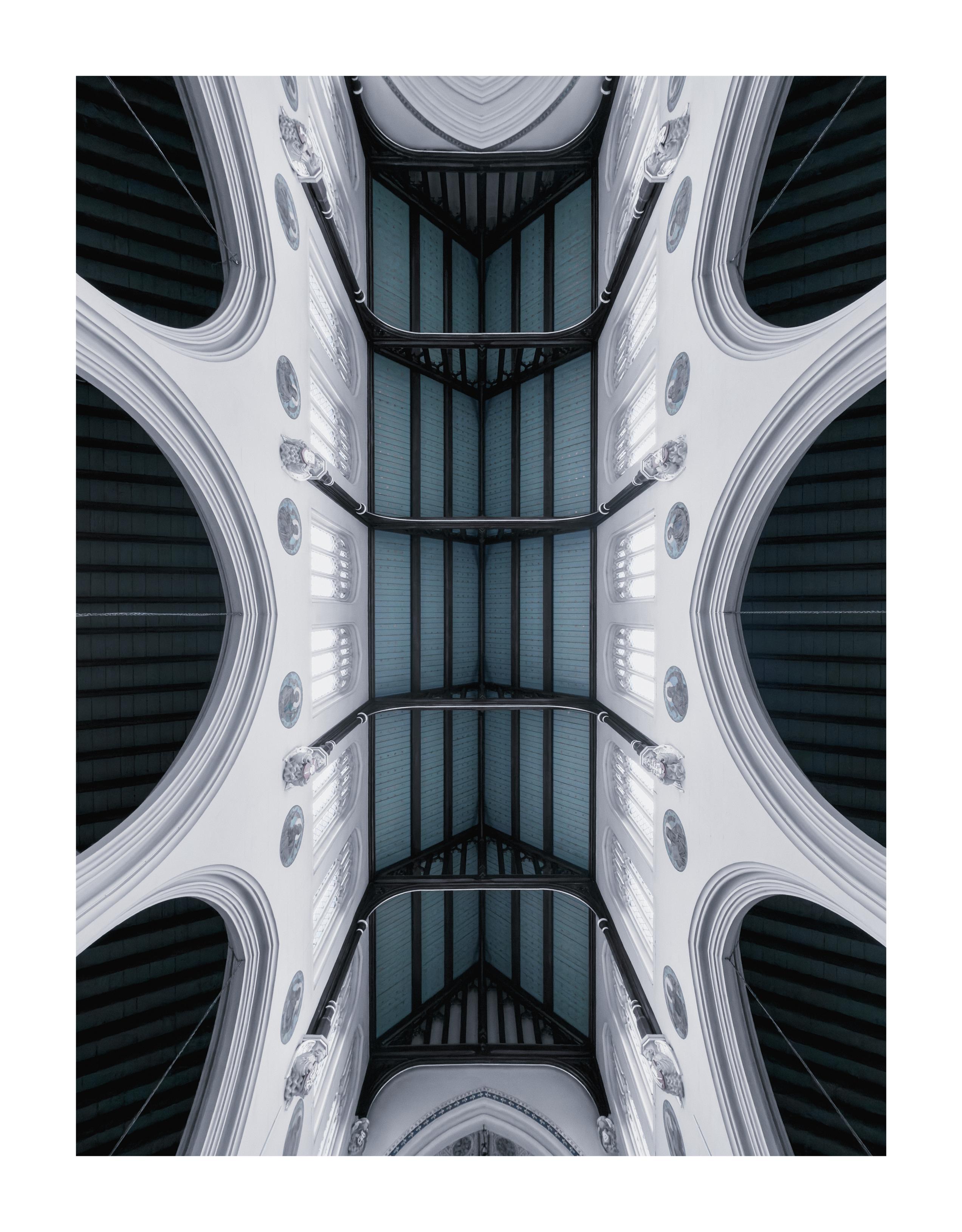 An ornate church ceiling in a Gothic architectural style with white arched walls.