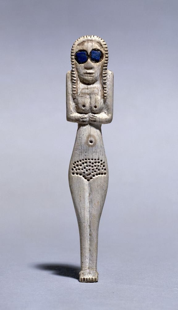 Bone figurine of a standing woman with doted pubic hair and with lapis lazuli inlays in her eyes that make her look as if she's wearing sunglasses.

It was made in Egypt by the Amratian culture, roughly between 3,900 and 3,700 BCE.