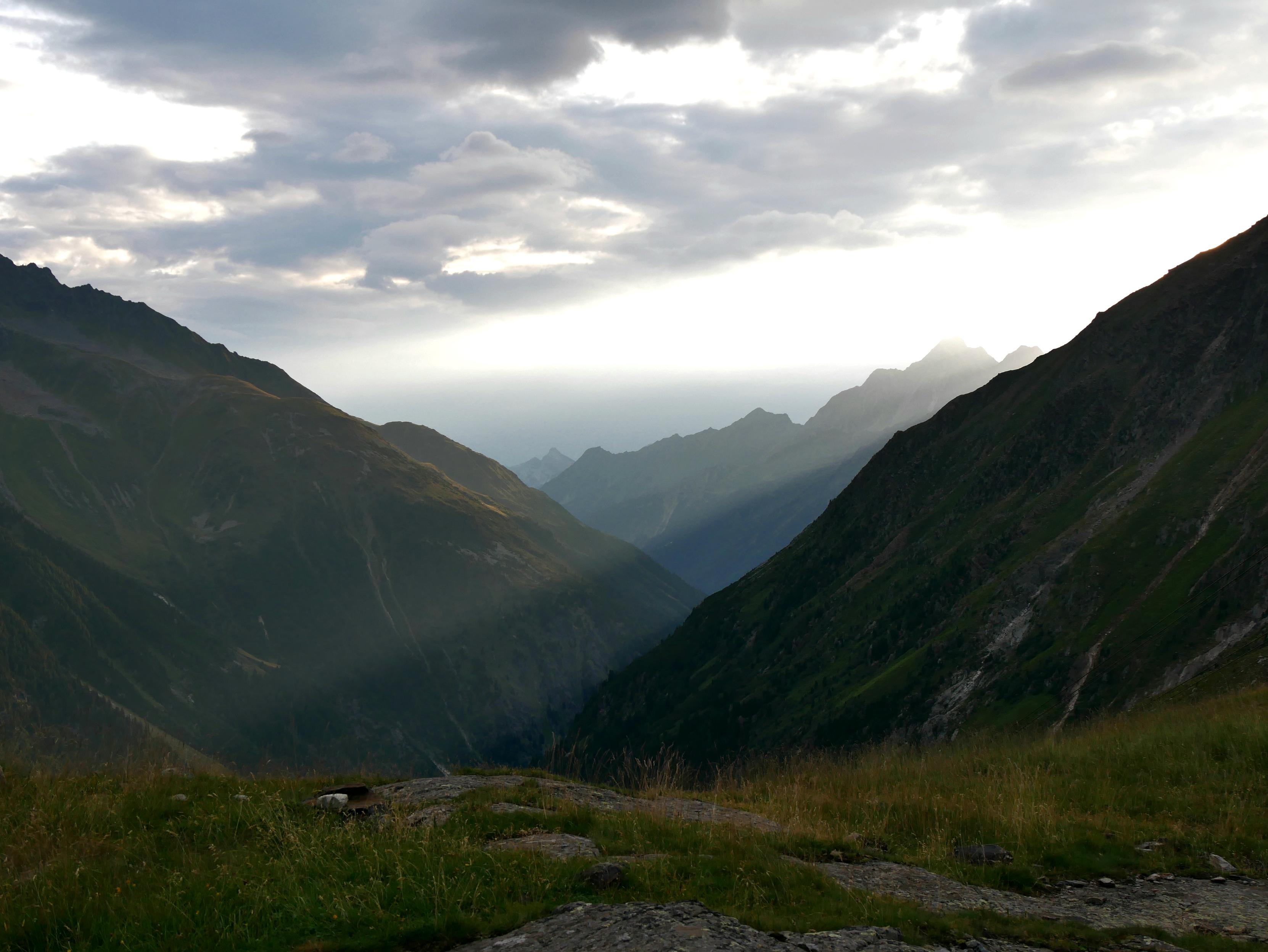 Die Morgensonne bricht über die östlichen Berge ins Tal hinab. Leichte Wolken ziehen über den Himmel. Stubaital 2026