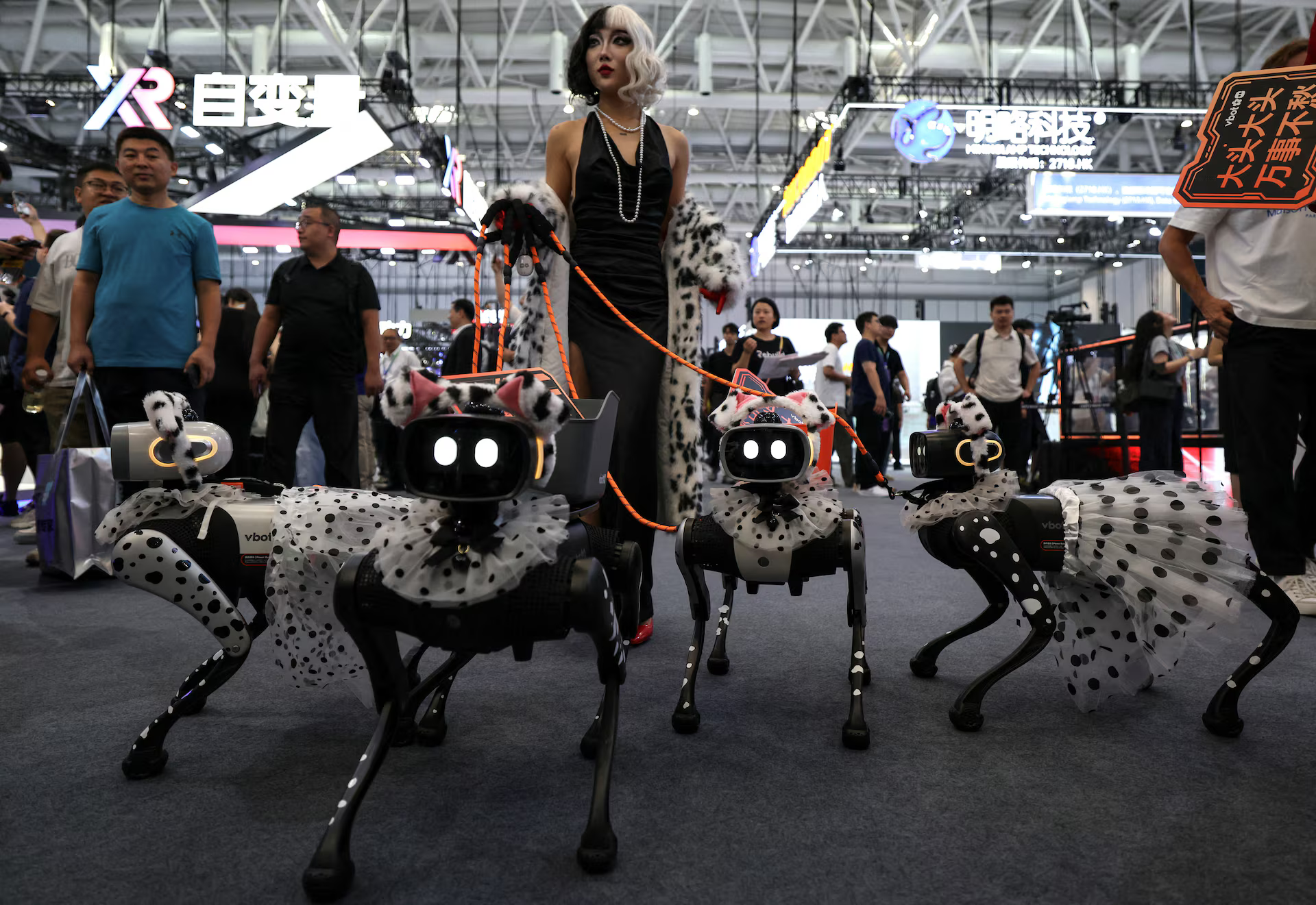 A staff member dressed up in a costume poses with VBot robots on a dog leash.