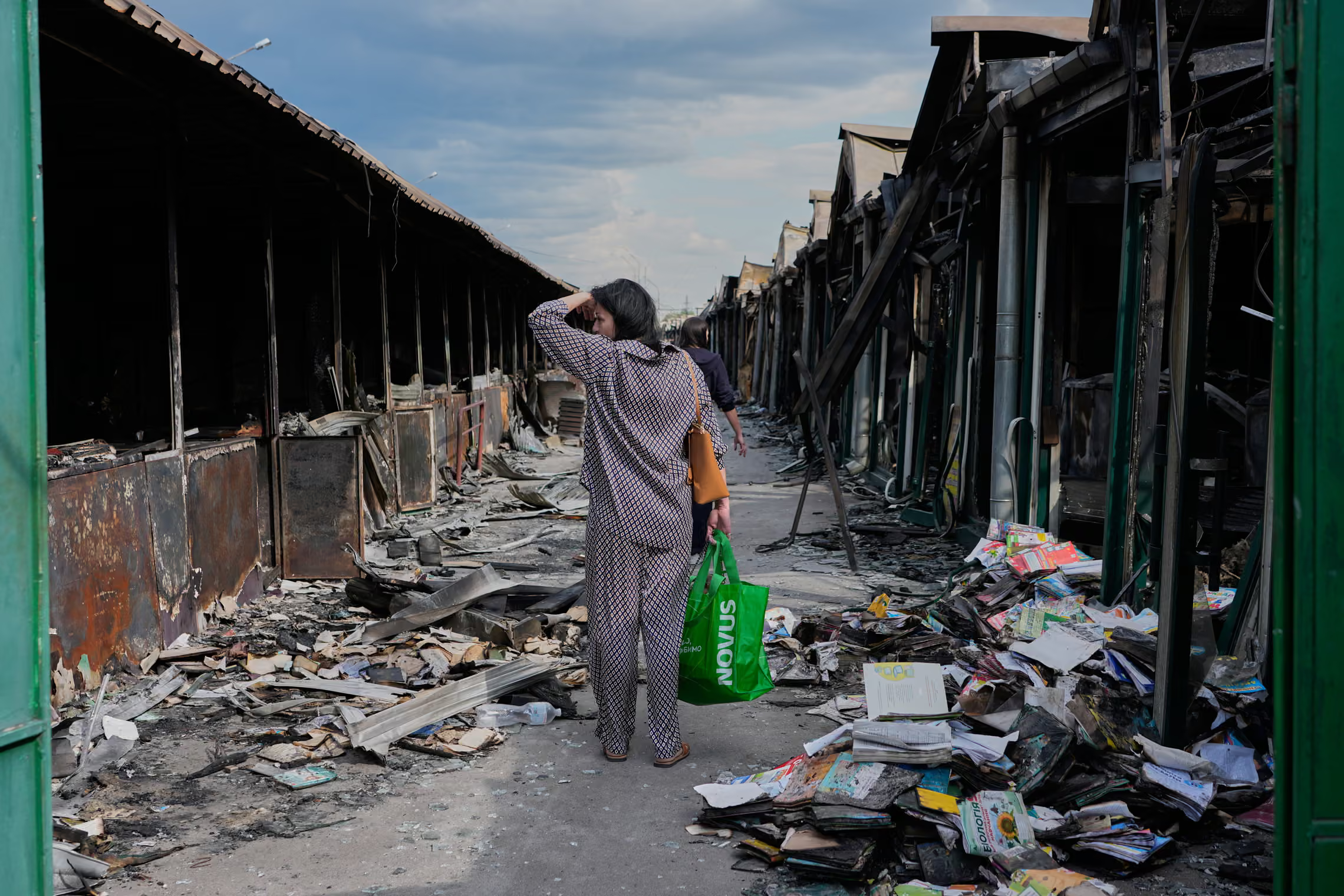 A woman walks by charred books at a book market.