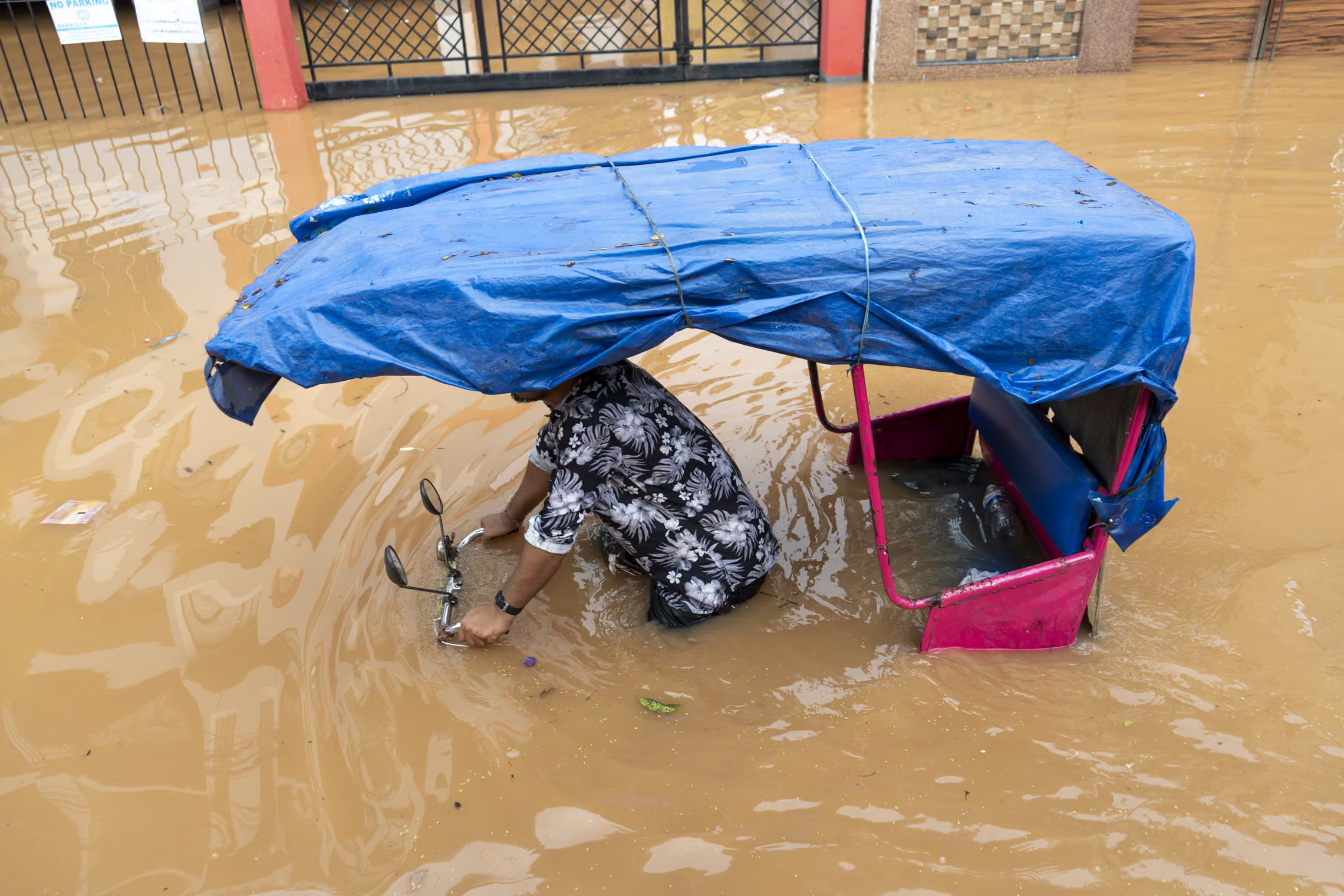 A cycle rickshaw driver navigates through flood waters.