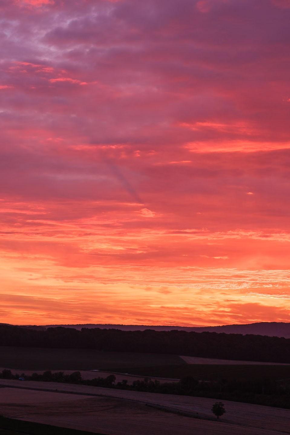 Avant le lever de soleil, dans un ciel rouge une ombre apparaît derrière un nuage