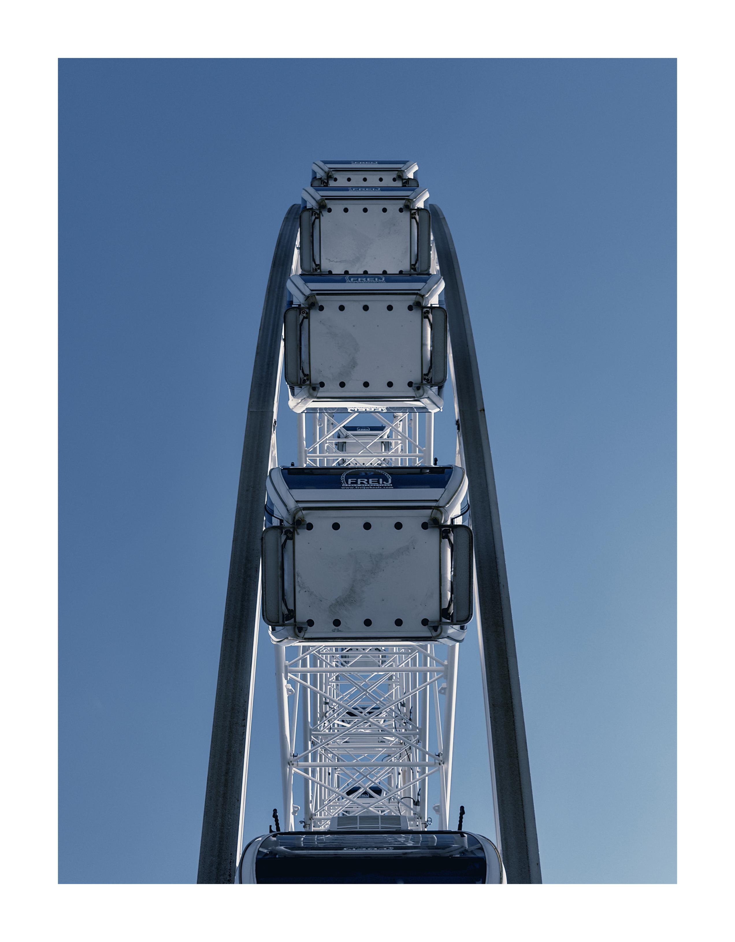 A big wheel shot from directly below to emphasise its symmetry against a plain blue sky background.