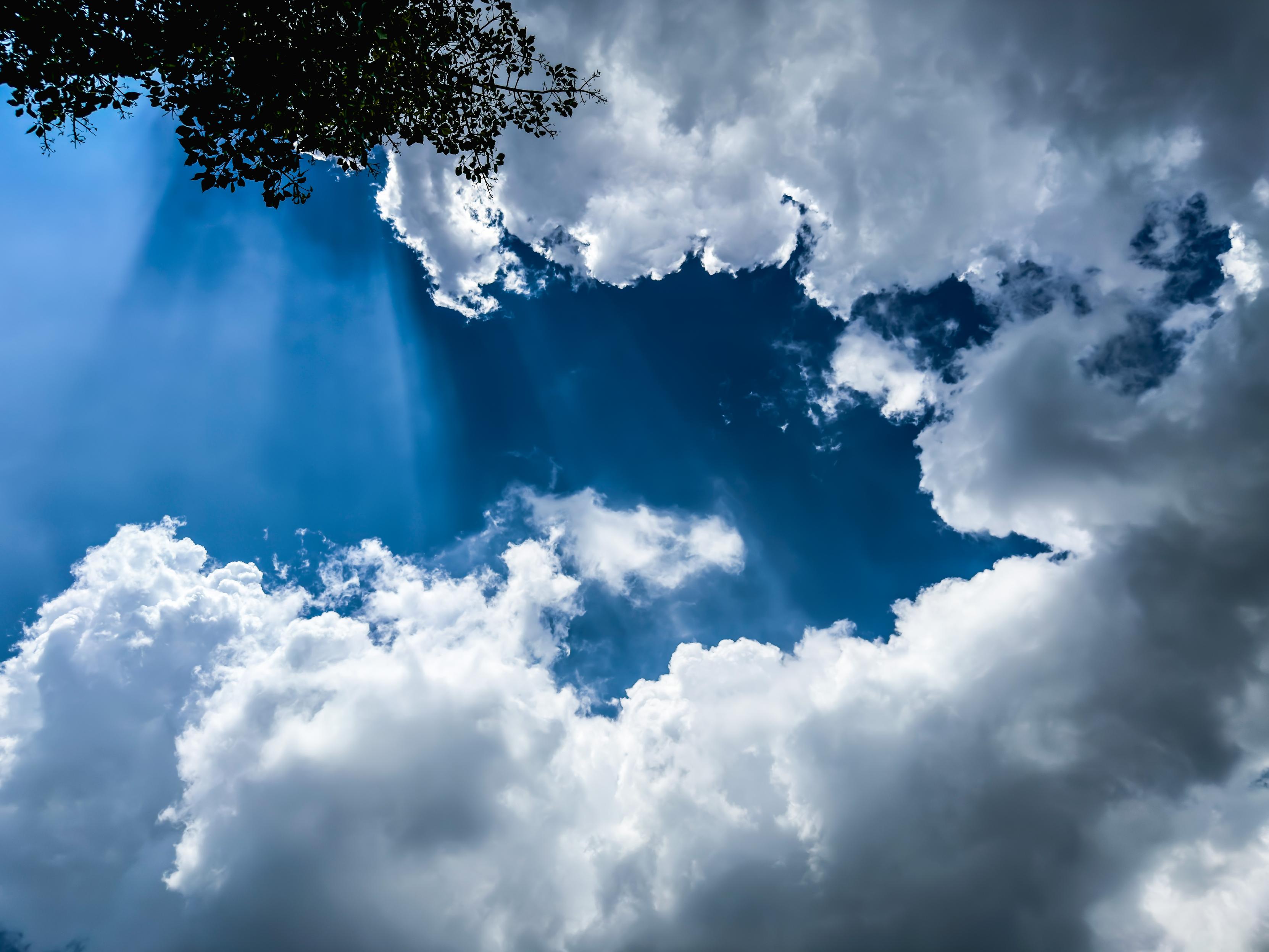 Cloudy sky with sun rays peeking through dark and light clouds.