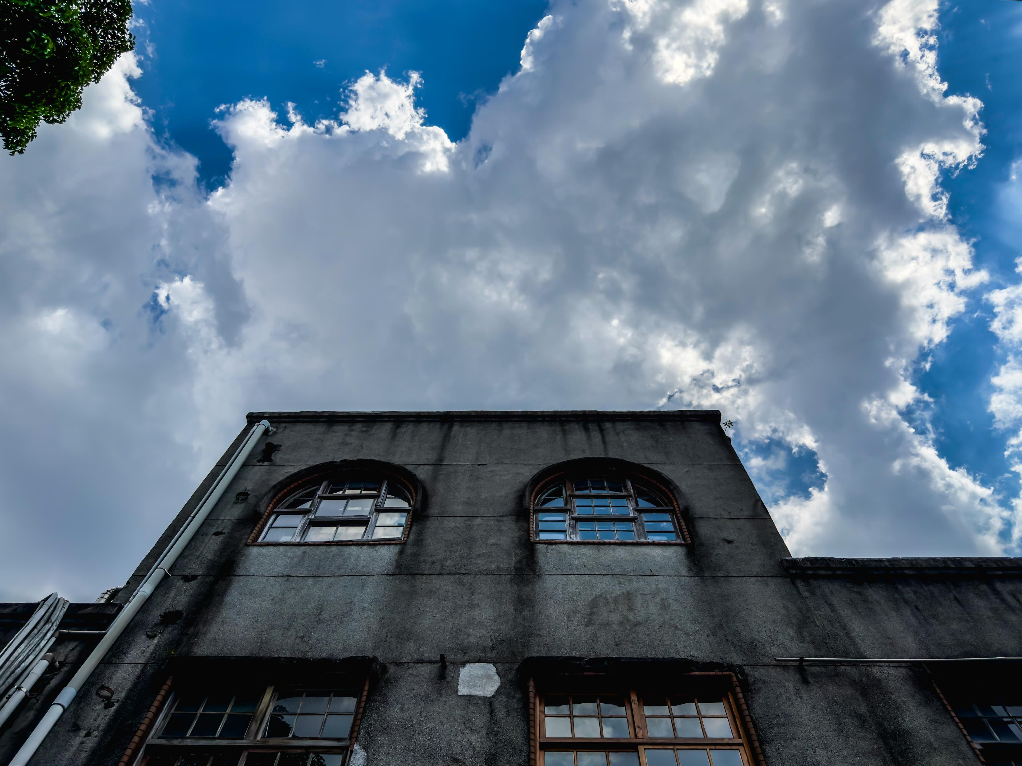 Old building with arched windows beneath a cloudy sky.