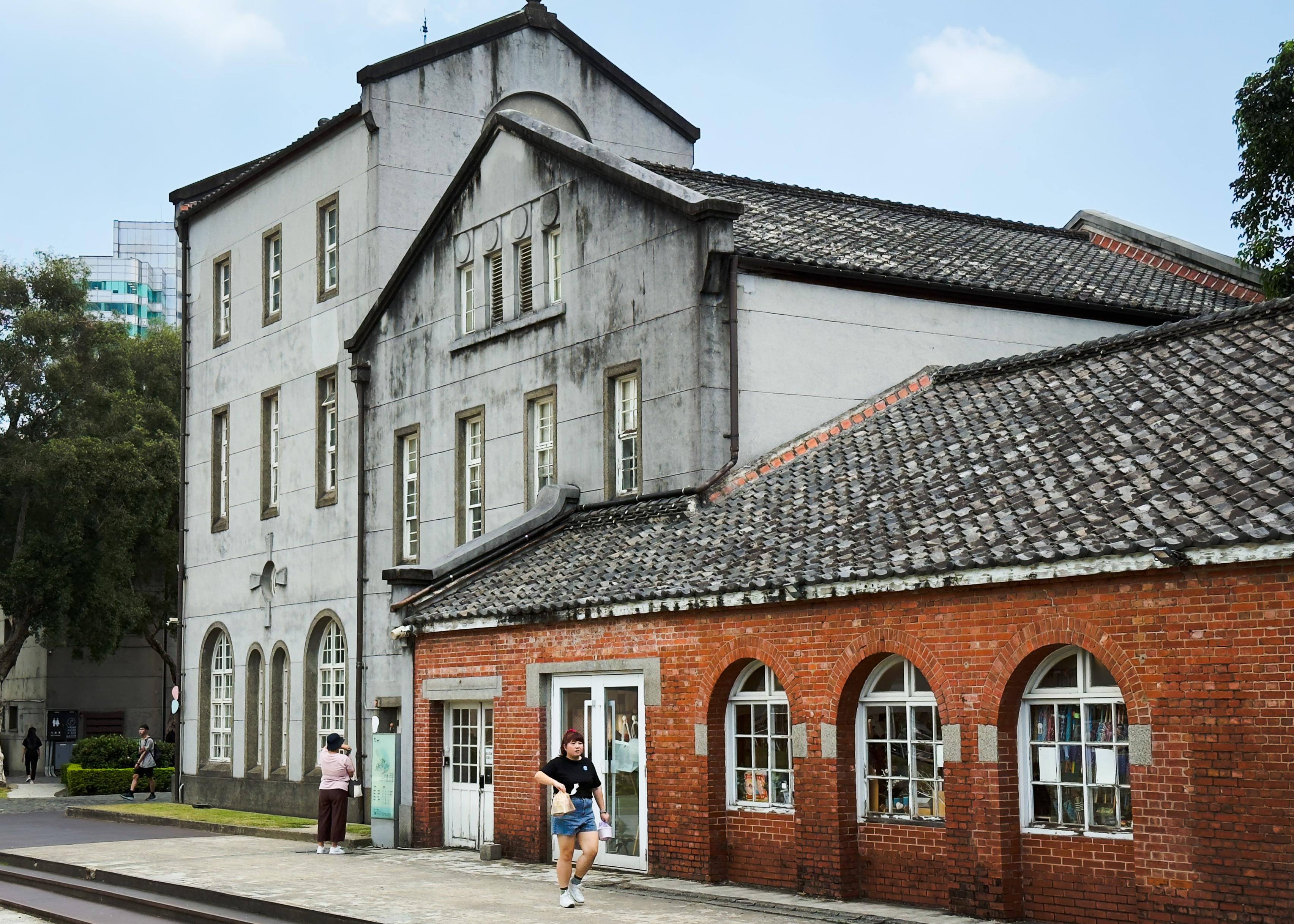 一栋由红砖和灰白色建筑组成的历史建筑。路边有人行走，环境宁静。