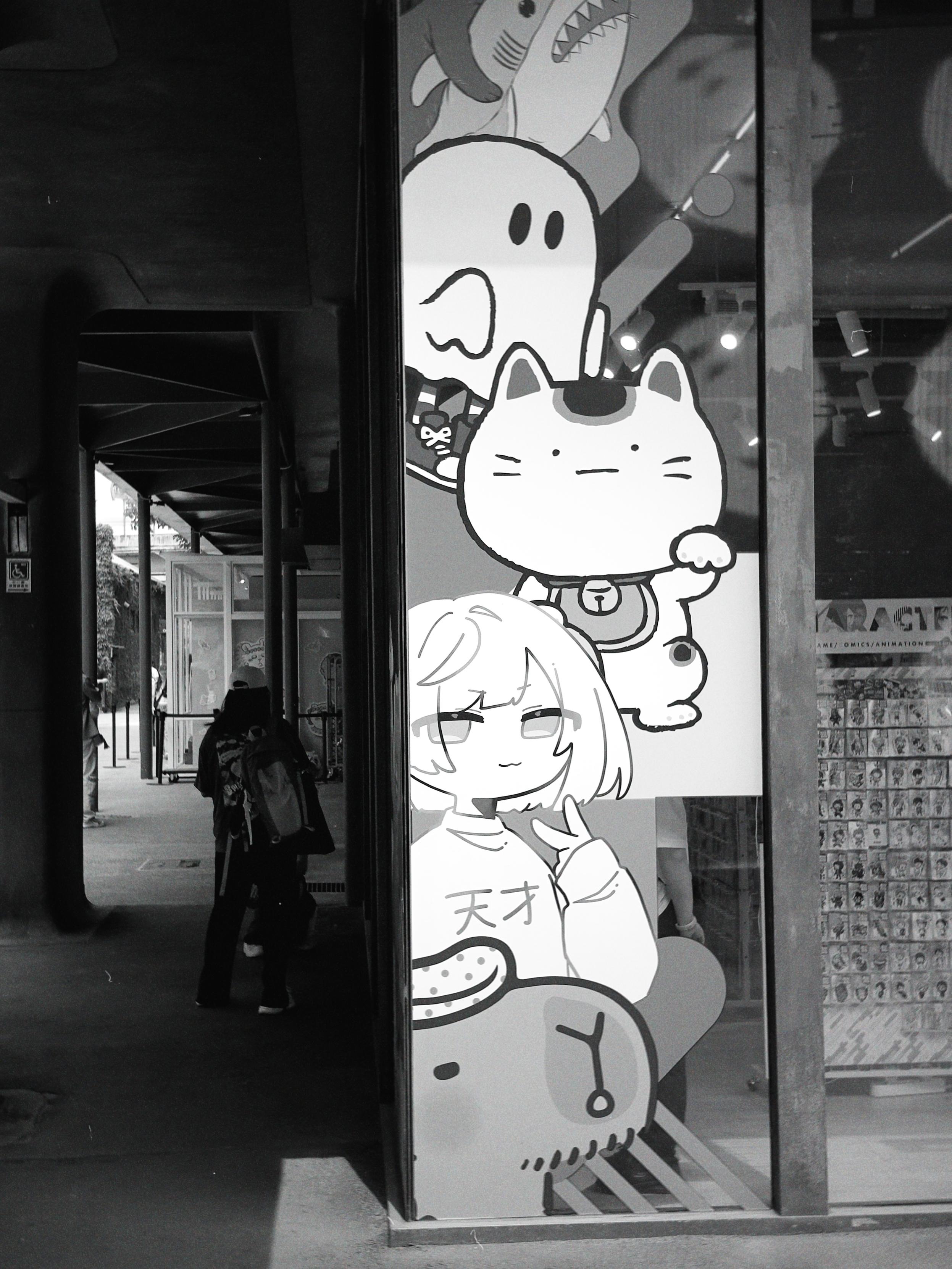 Black and white illustration of a person with short hair, sitting and smiling, with cartoon characters behind them and on a wall.