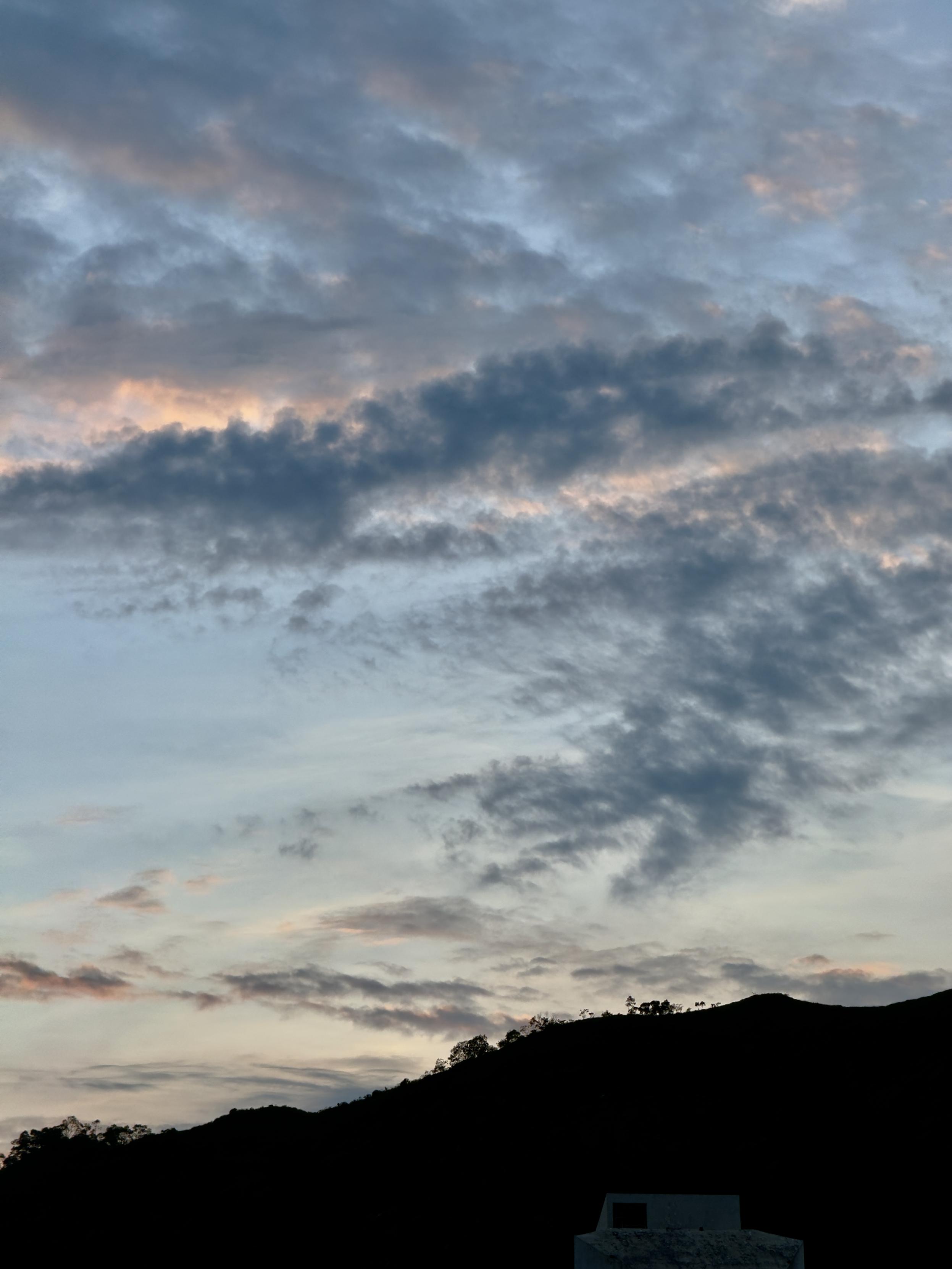 夕阳下的云彩，山脉轮廓，天空中布满了彩色的云朵。