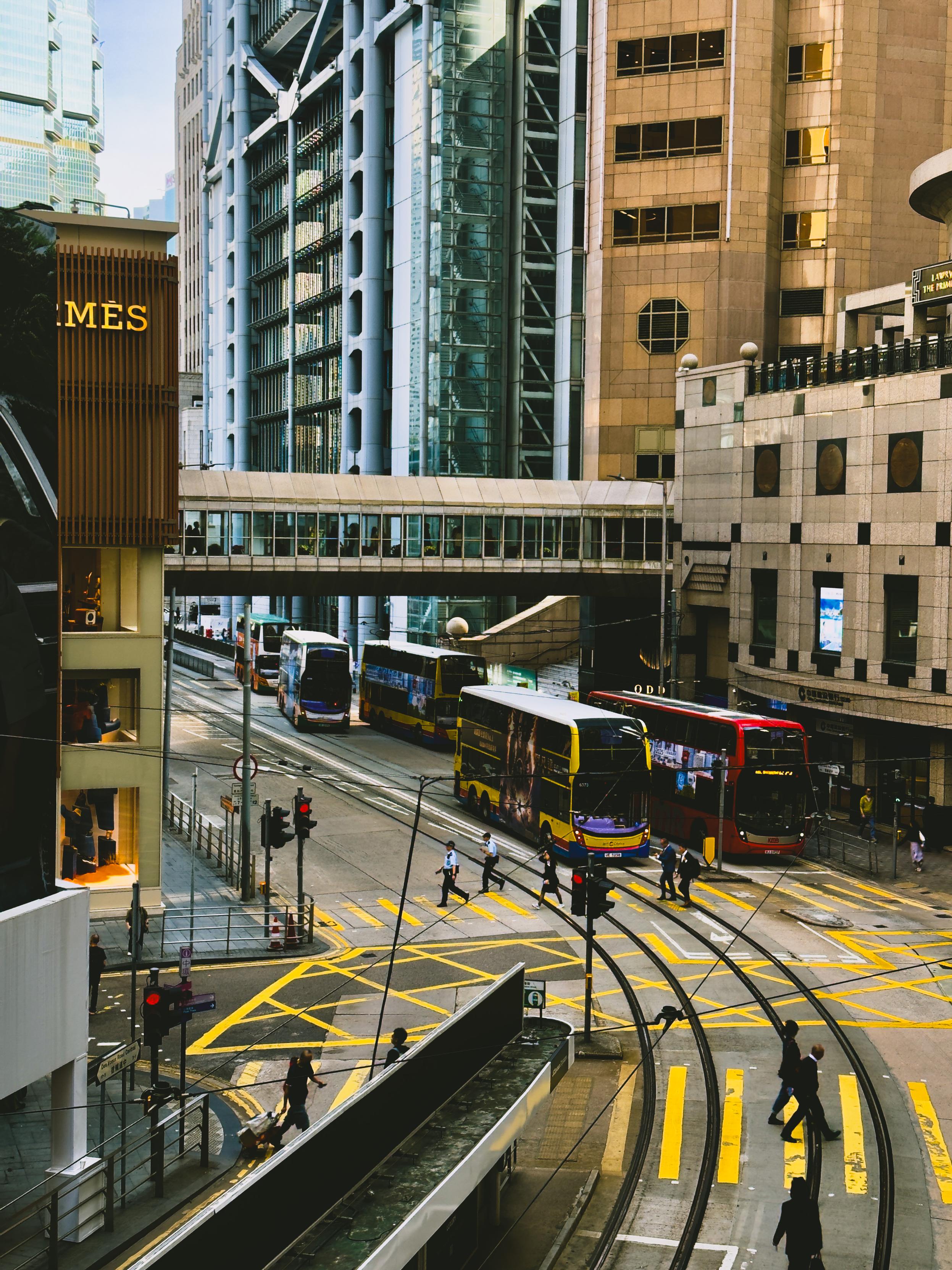 繁忙的都市街道，有公交车和行人穿越交叉路口。高楼林立，城市繁华景象。