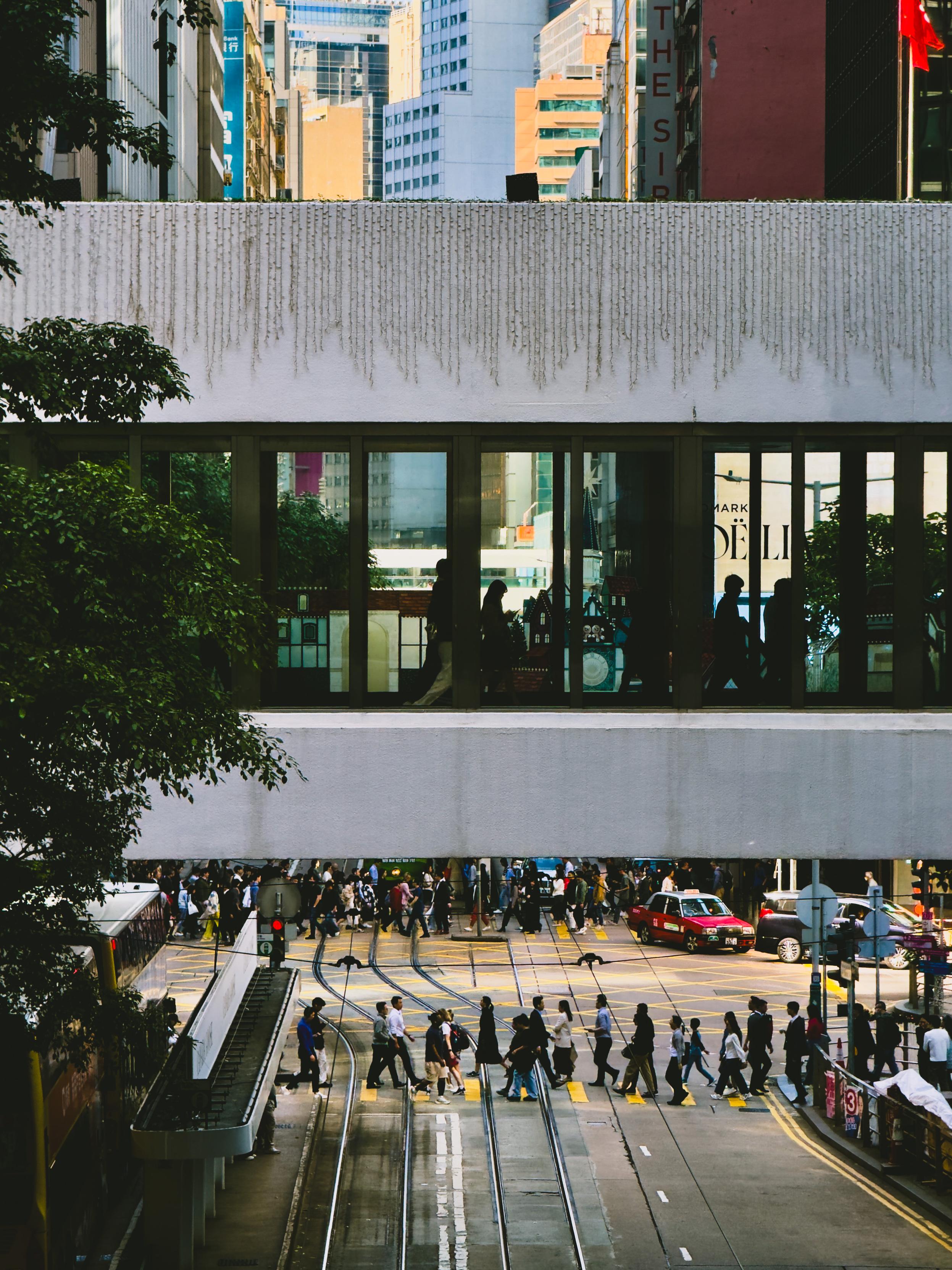 繁忙的城市街道上行人穿越斑马线，背景是一座高层建筑和现代化的城市景观。