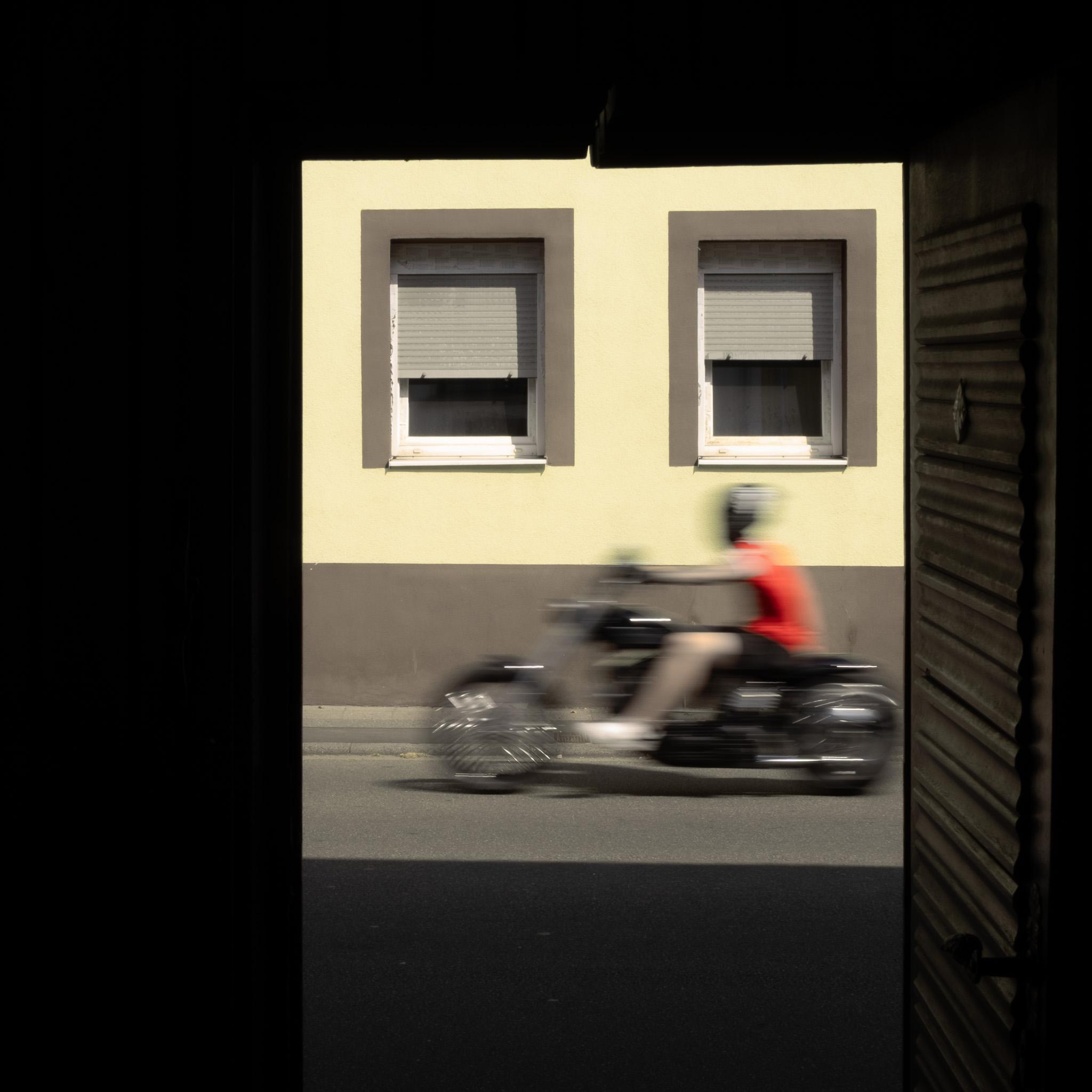 Ein vorbei fahrendes Motorrad - durch eine offene Tür beobachtet.