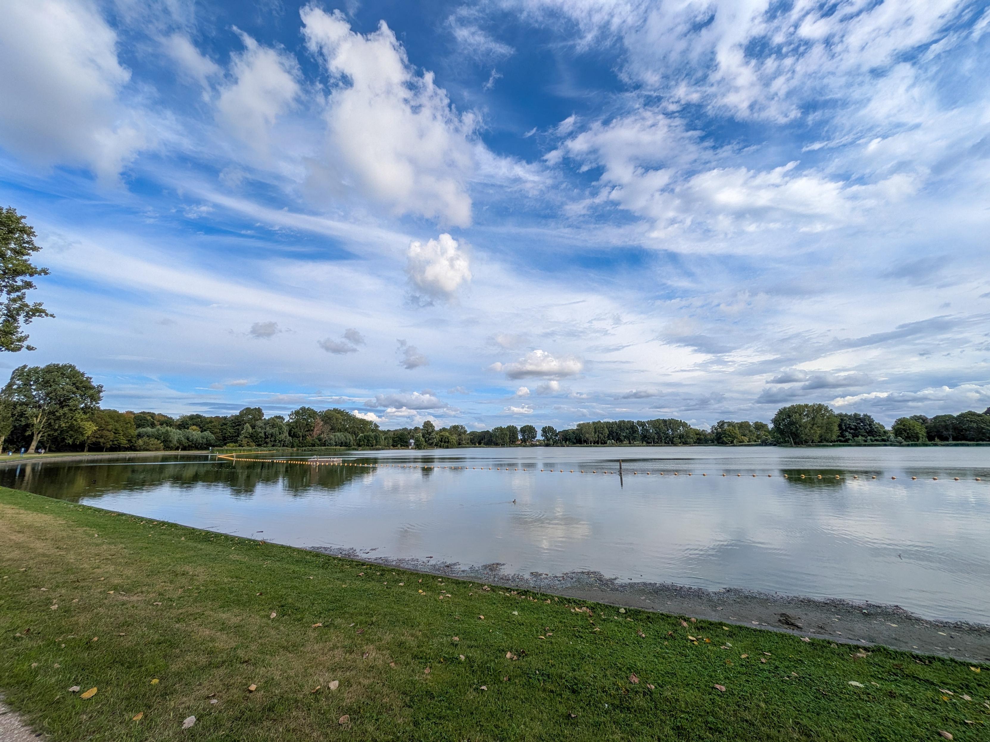 Waterplas met gras ervoor en een wolkenlucht