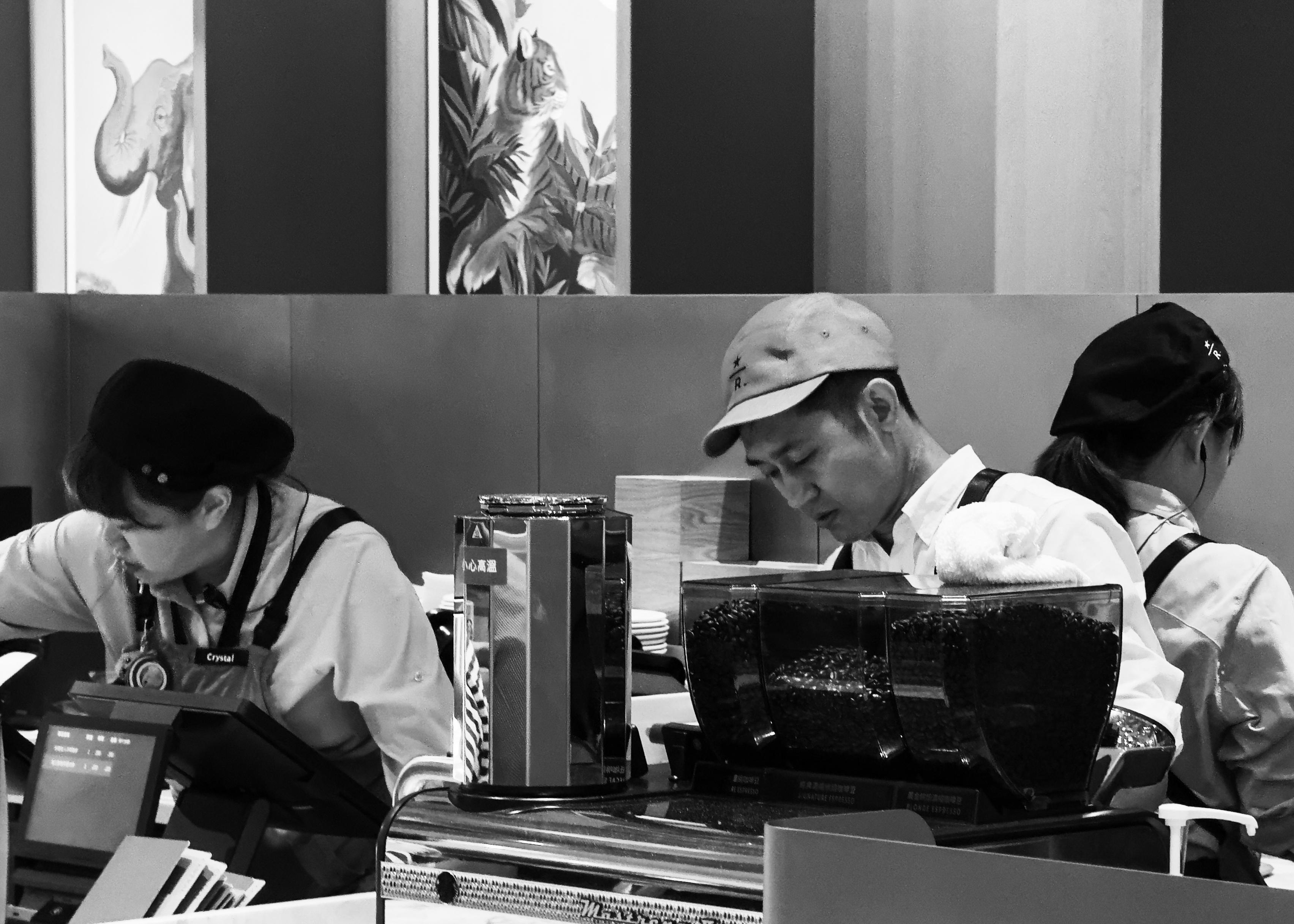 三位员工在咖啡店柜台工作，专注于手头的任务。