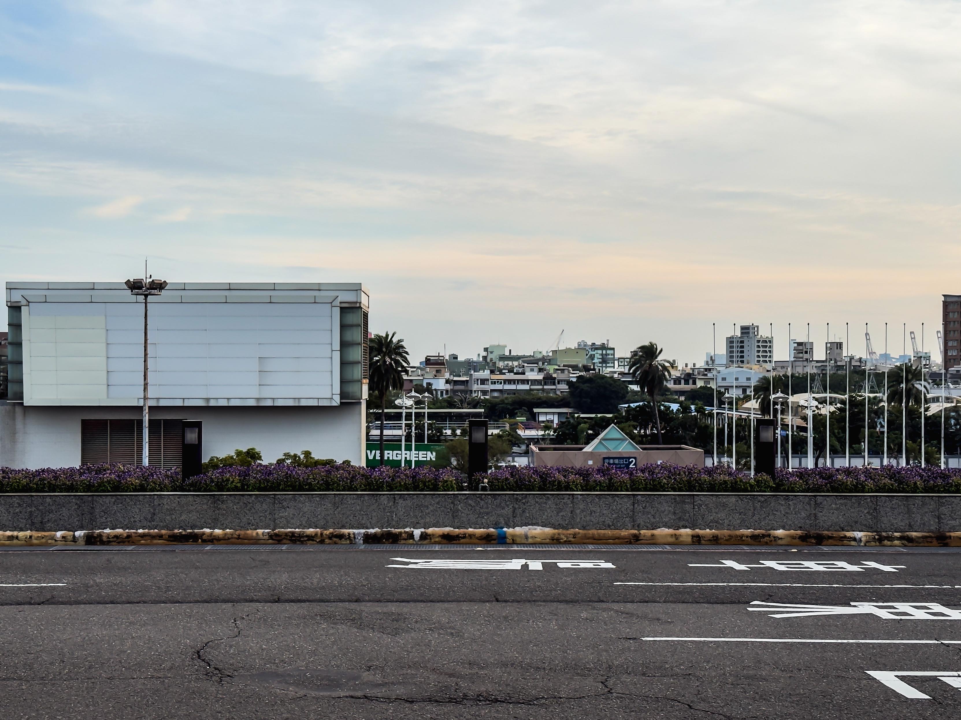 城市道路，背景是建筑物和树木，天空多云。