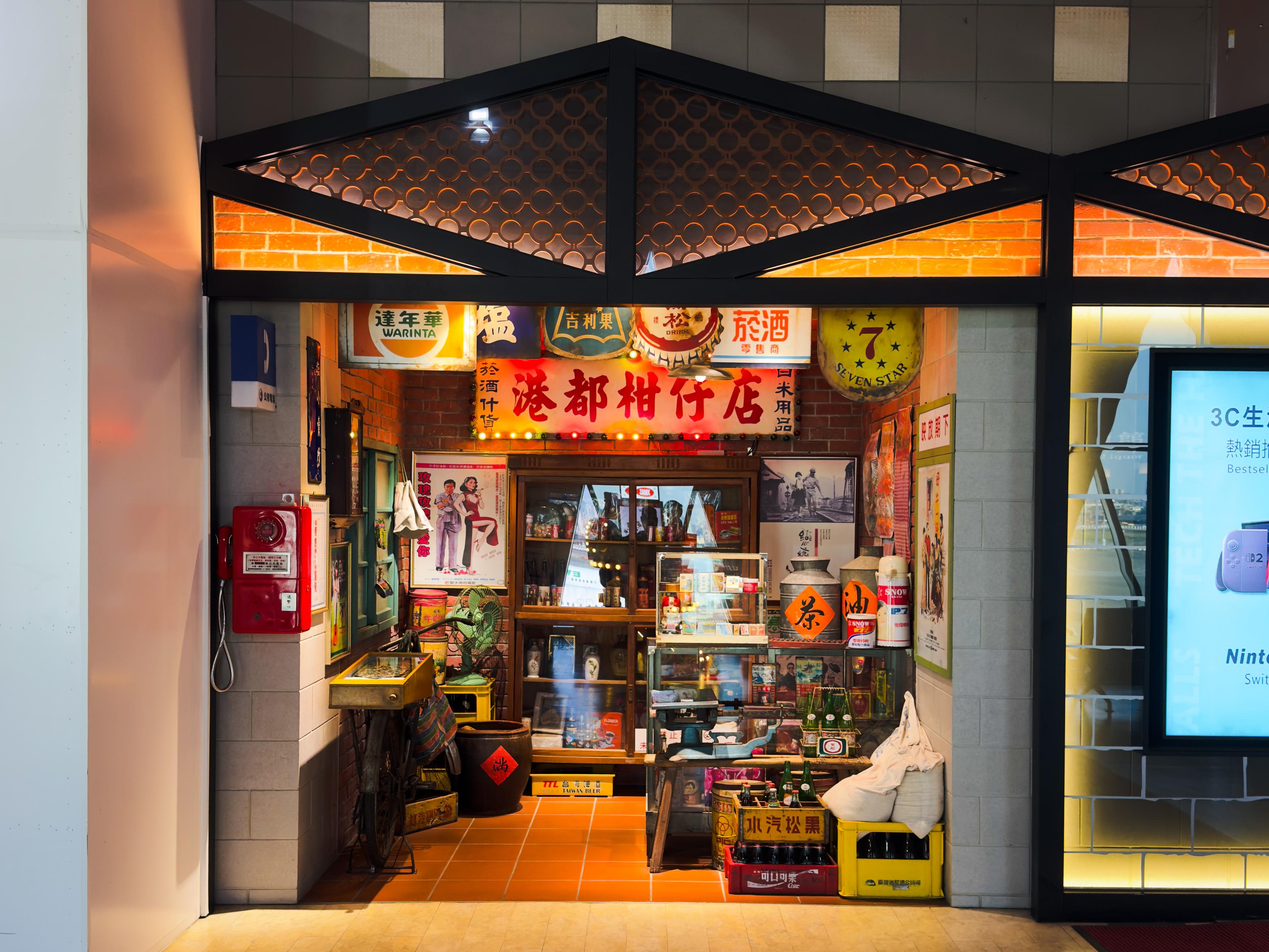 这是一个装饰有各种招牌和商品的小型商店，门口摆放着瓶子和箱子，墙壁上有彩色海报和图片。