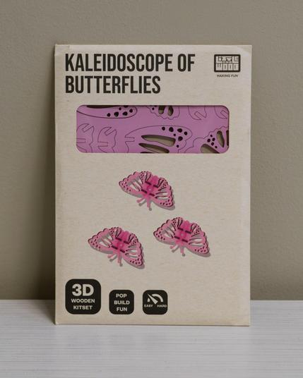 Brown envelope that reads Kaleidoscope of Butterflies with a plastic window showing a flat surface of scored purple wood and three butterfly models made from the kit.