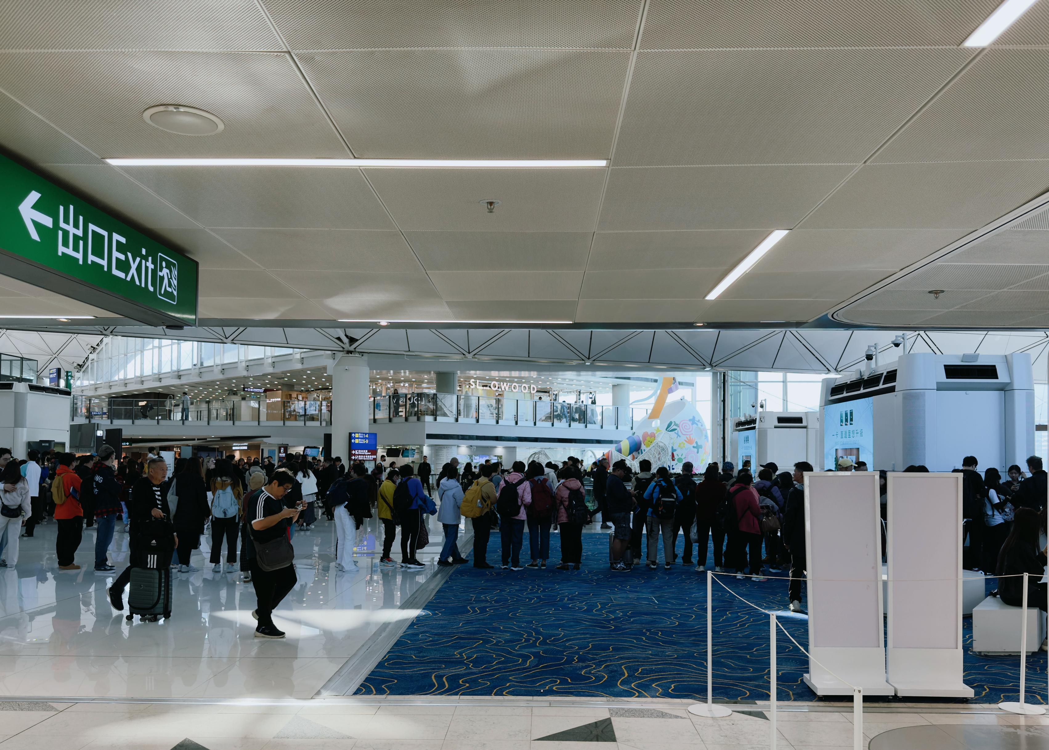Crowd of people lined up at an airport security checkpoint, with some waiting and others walking through.