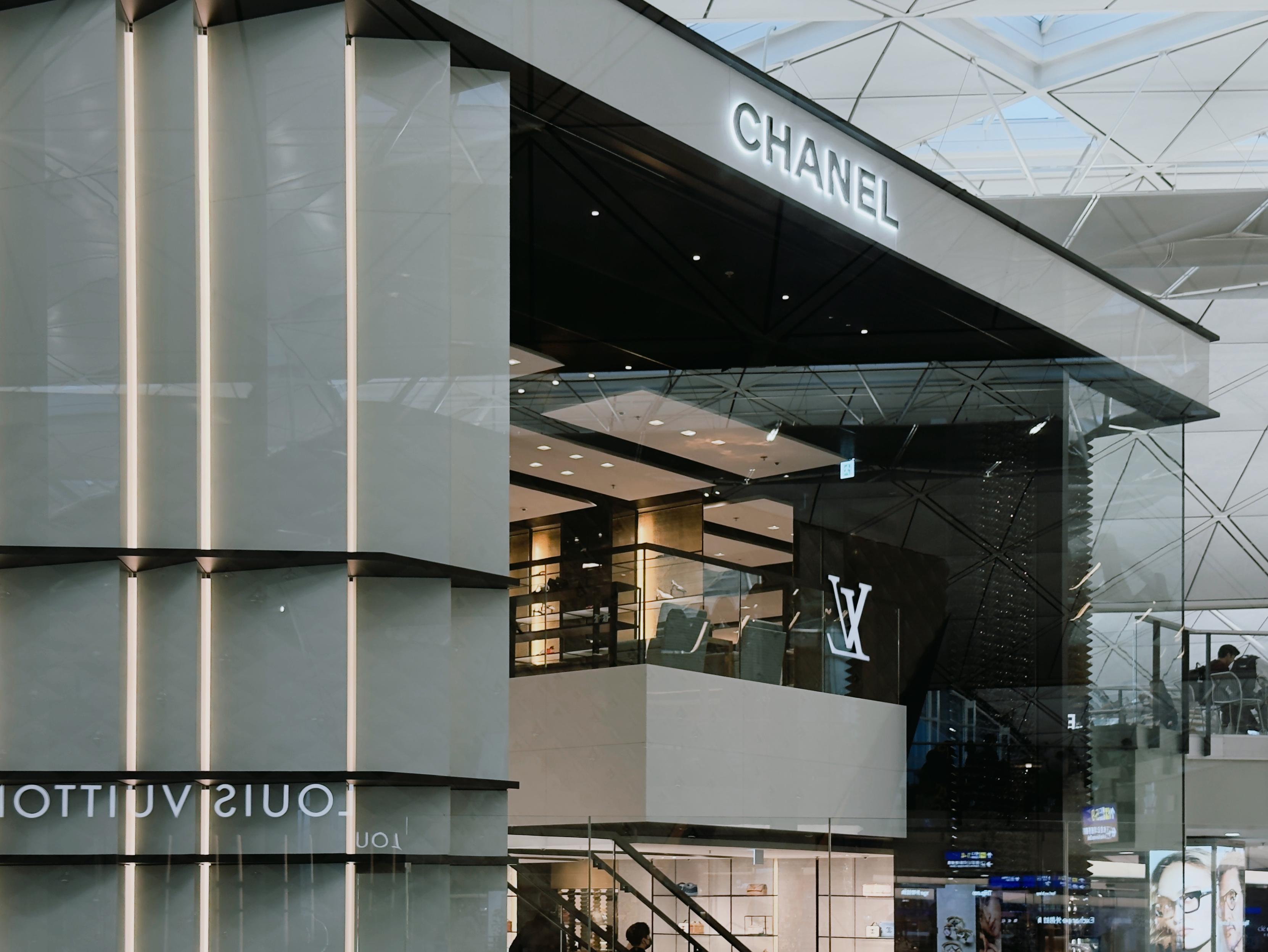 Exterior of a luxury shopping mall, featuring a Chanel store with modern architecture and glass elements.