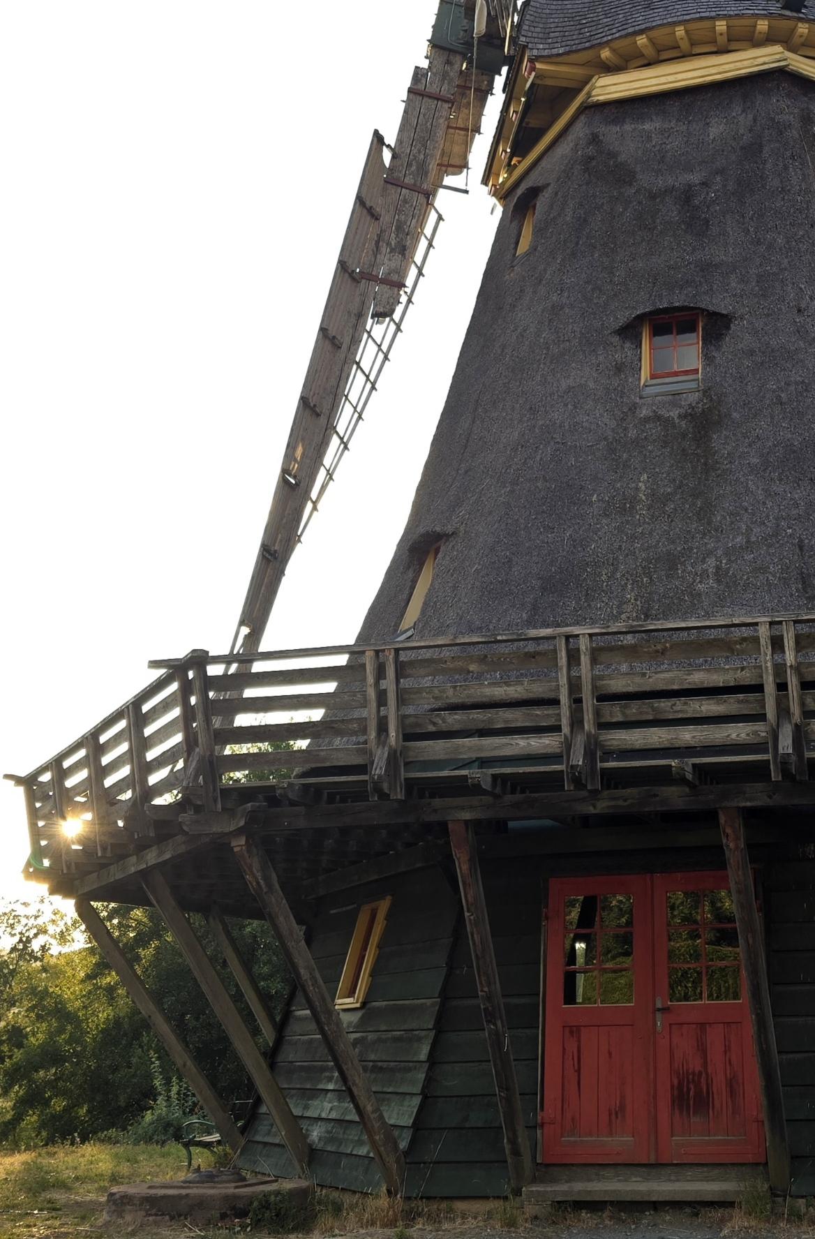 Blaue Stunde. Fast wolkenloser Abendhimmel. Alte Mühle. Fokus auf den linken Mühlenteil mit untergehender Sonne.