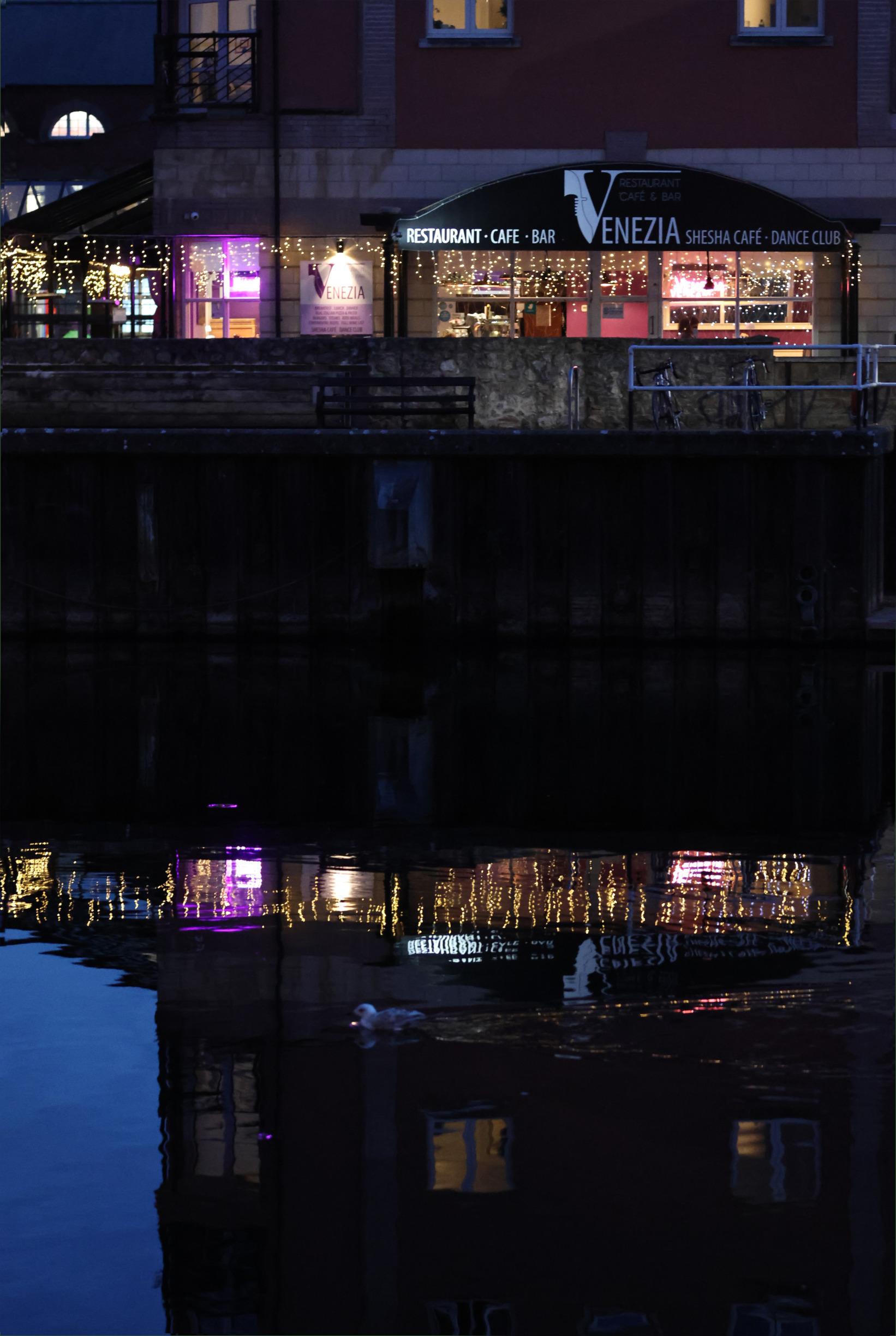 A  restaurant lights are reflected in the river