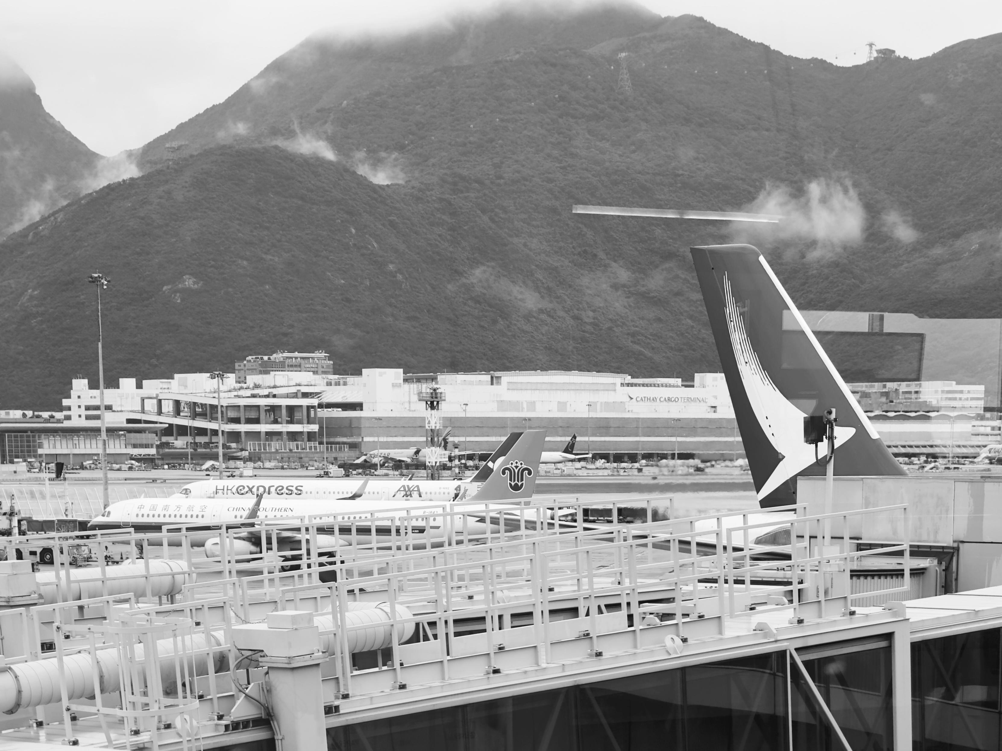 香港国际机场，山脉背景，多架飞机停靠登机口。