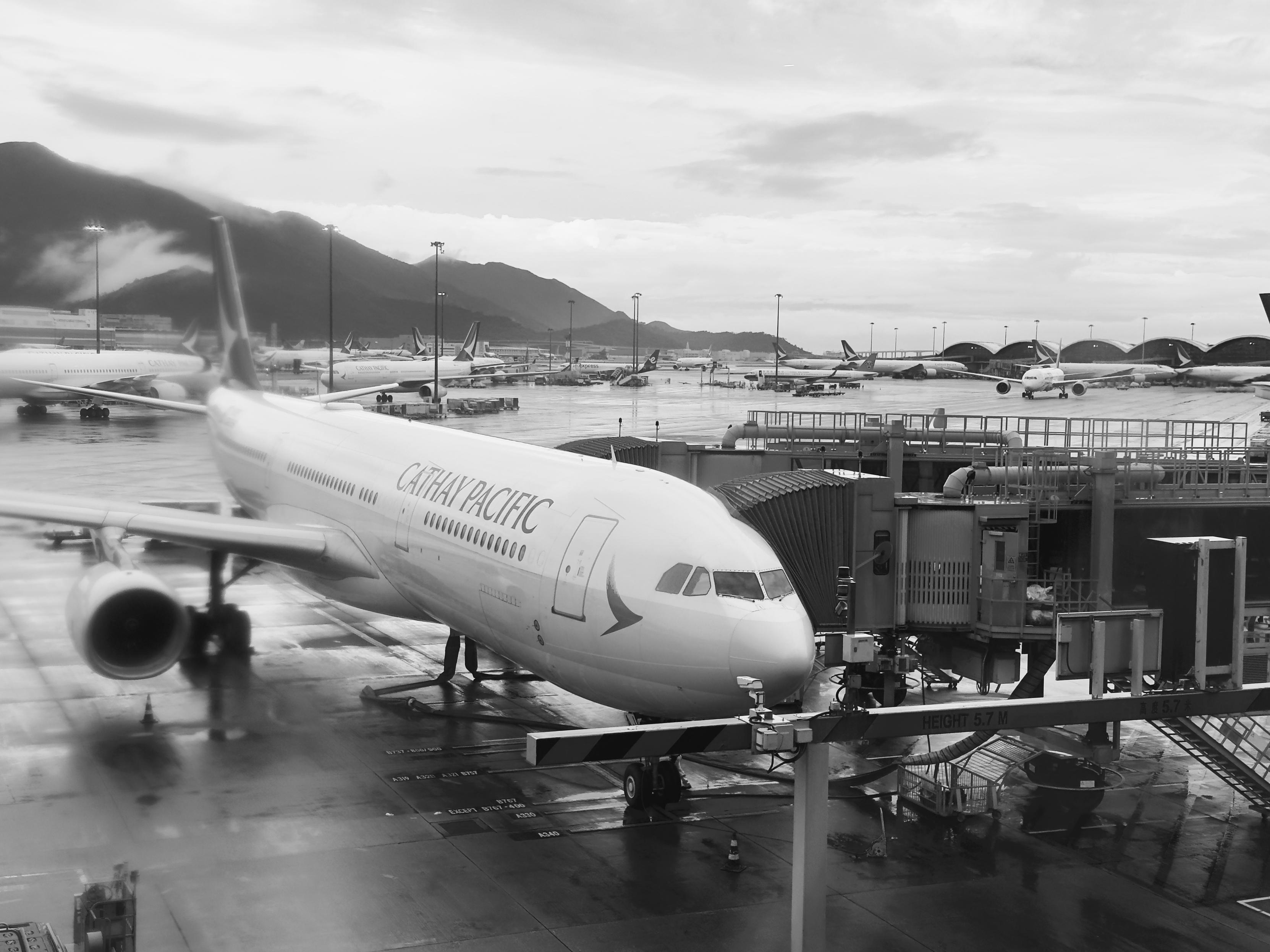 香港快運航空的飛機停靠在機場候機樓，背景是多架飛機和山脈，天氣多雲。