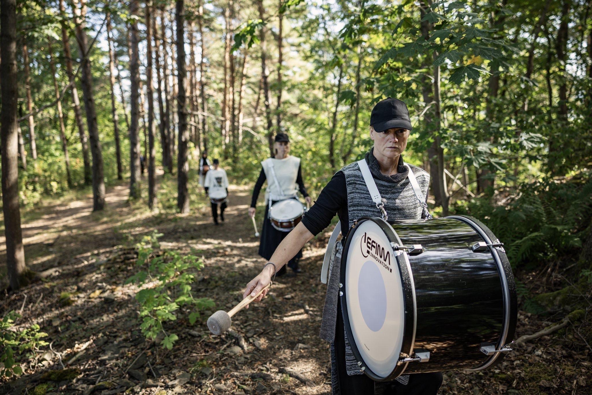 Dancers with marching drums performing in a forest.